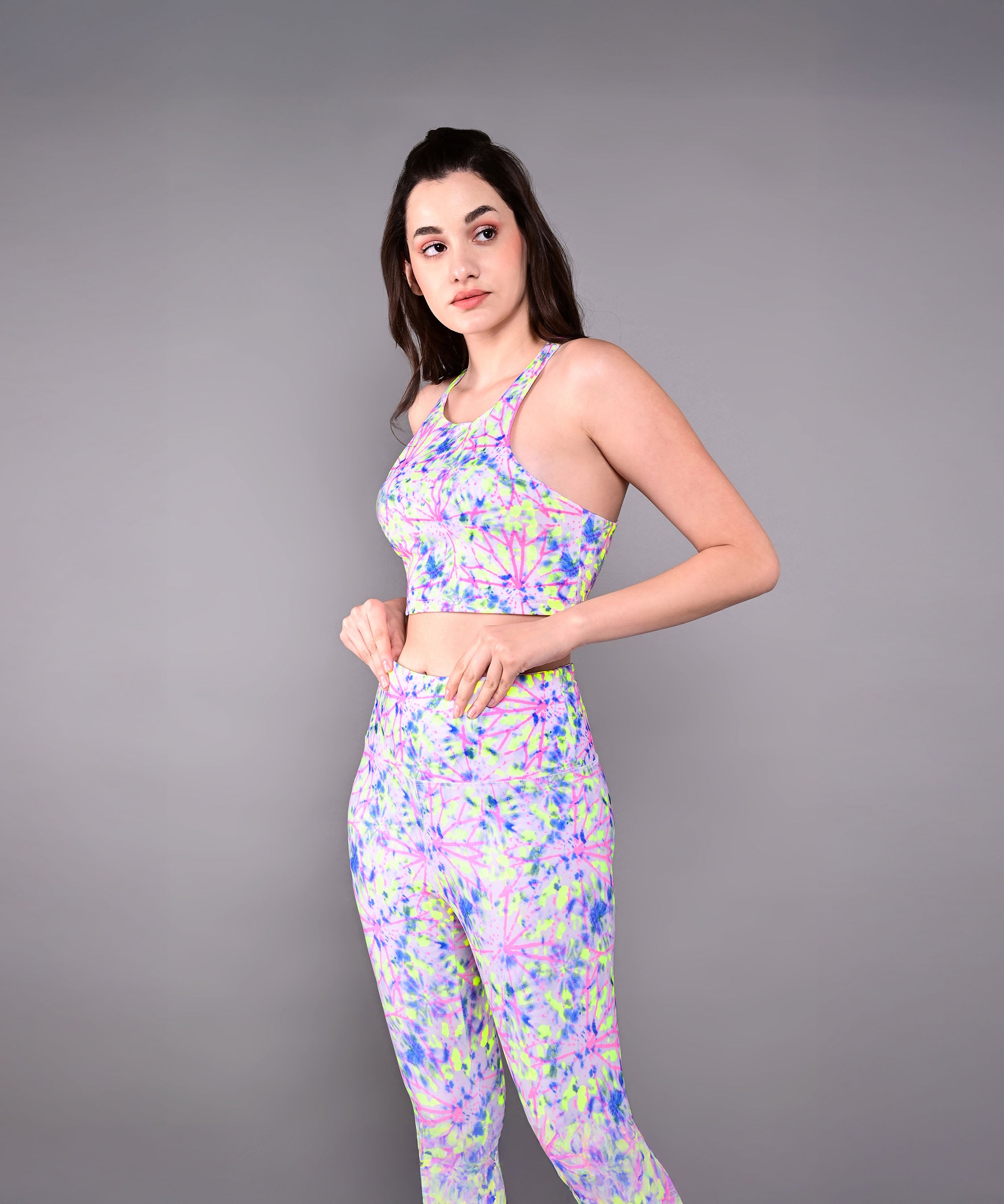 Woman wearing the Multicolor Neon Crop Top, made from skin-friendly cotton lycra, stands sideways against a plain gray background.