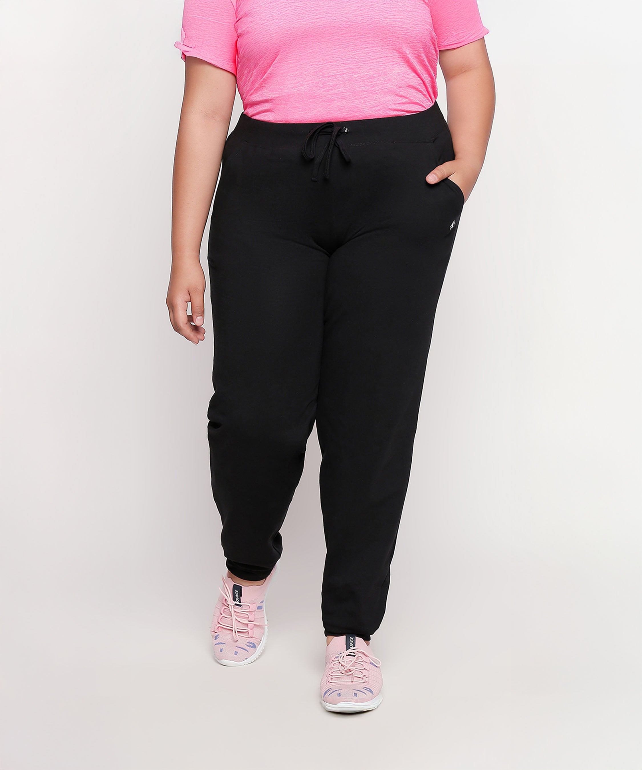 Person wearing a pink shirt, Classic Joggers - Plus Size 02, and pink sneakers stands against a plain background.