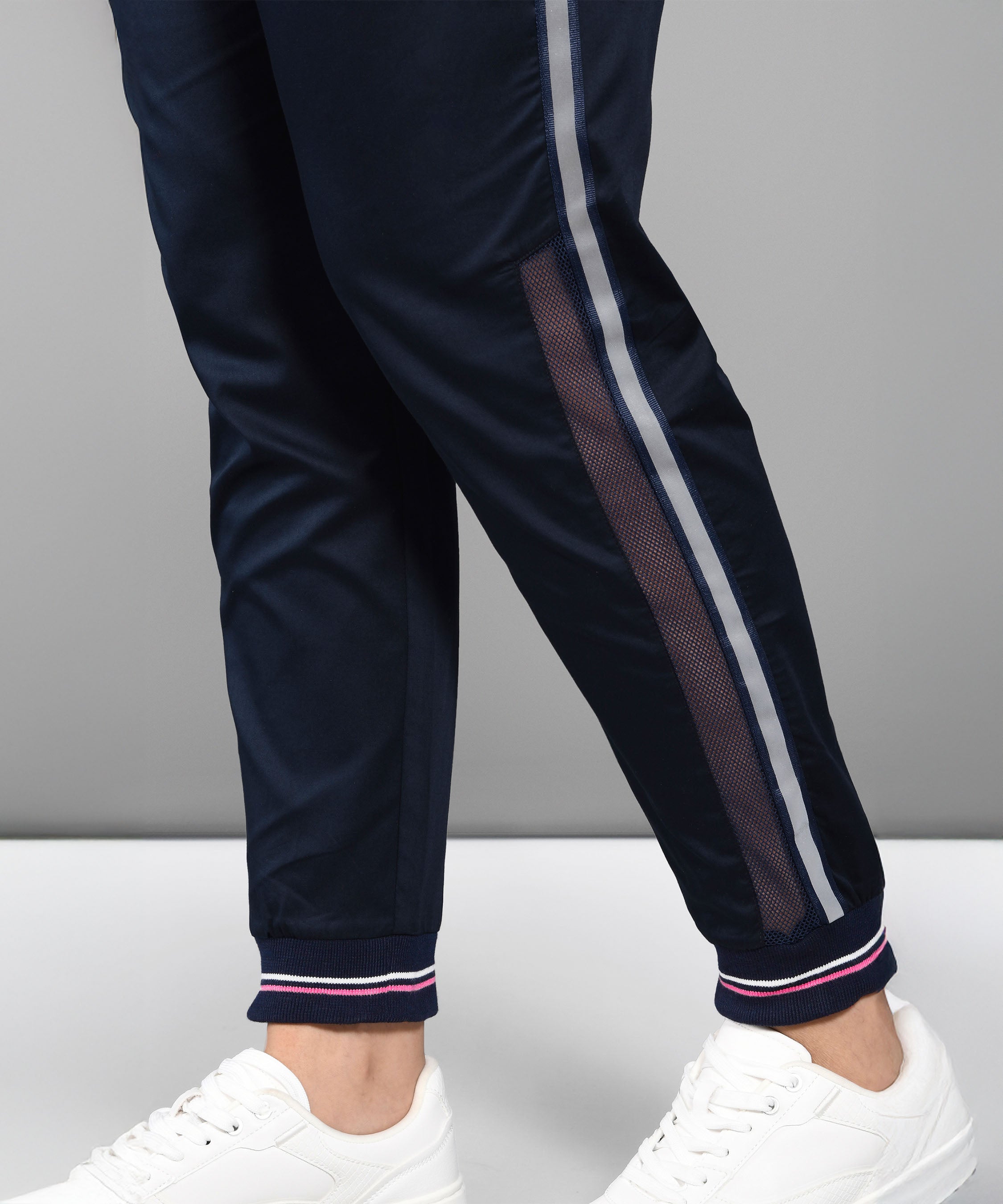 Wearing the Accented Set—navy striped track pants and a matching batwing sleeve shirt—a person pairs it with white sneakers, standing against a gray background.