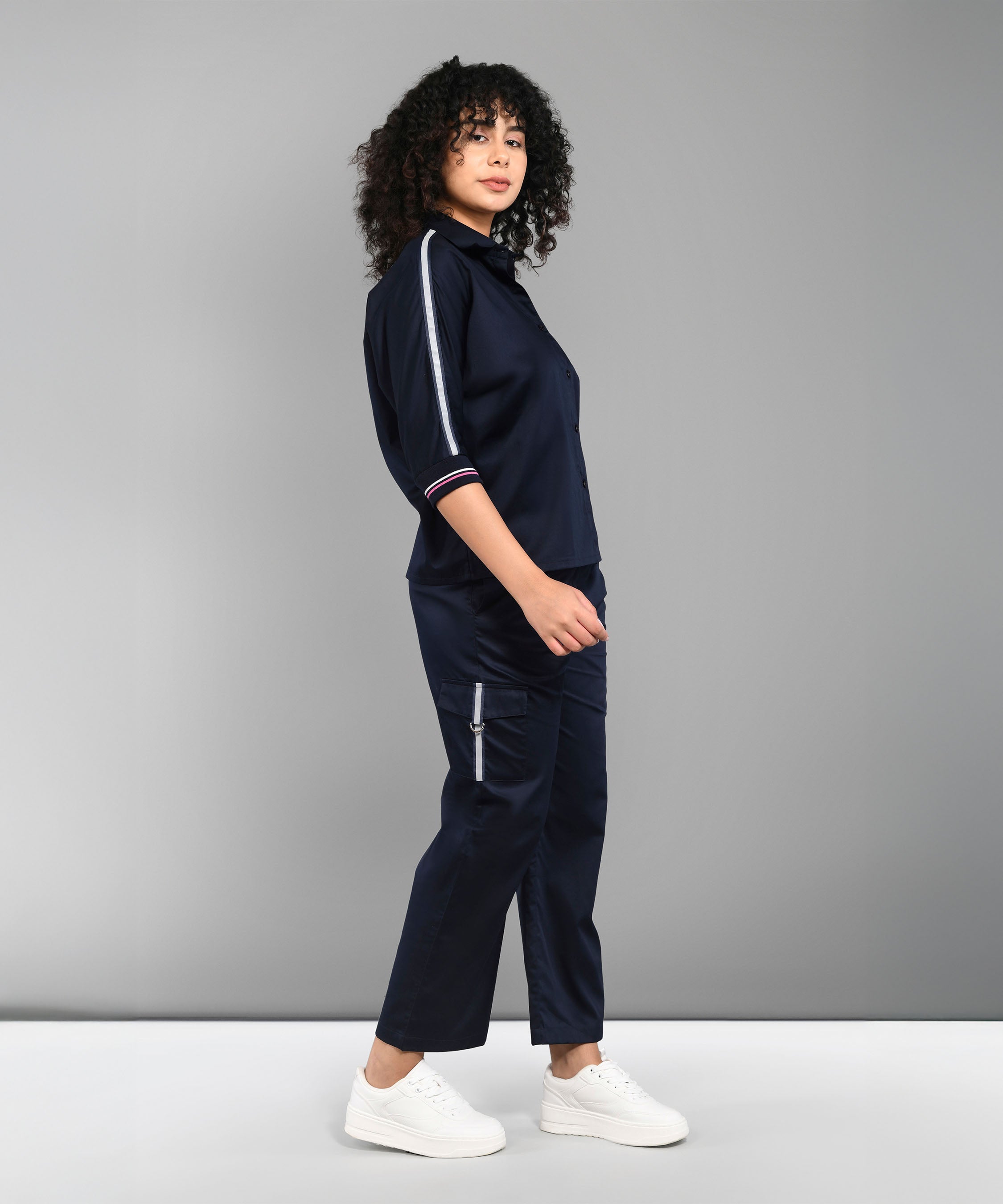 A woman models the Navy Blue Chic Set with white sneakers, posed sideways against a grey backdrop.