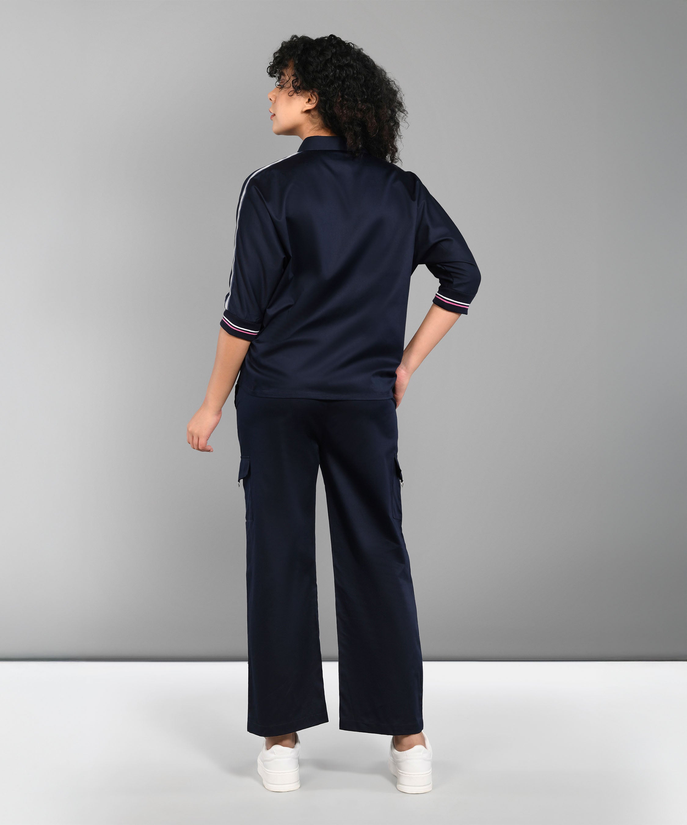 A person wearing the Navy Blue Chic Set with track pants and white sneakers stands facing away against a plain gray background.