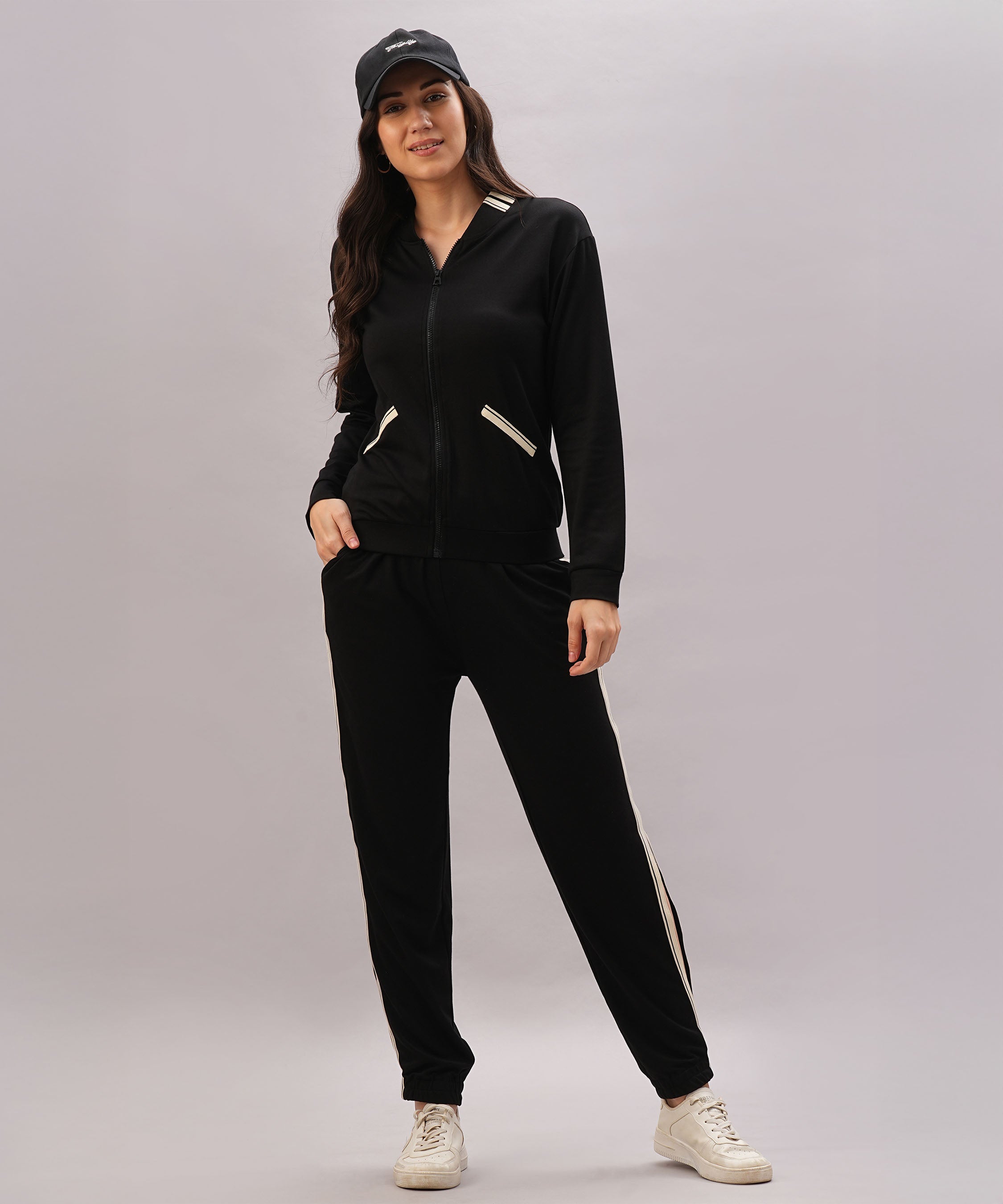 A woman wearing the Black Co-Ord Set pairs it with white sneakers and a black cap, smiling against a plain background to showcase this stylish coordinated outfit.