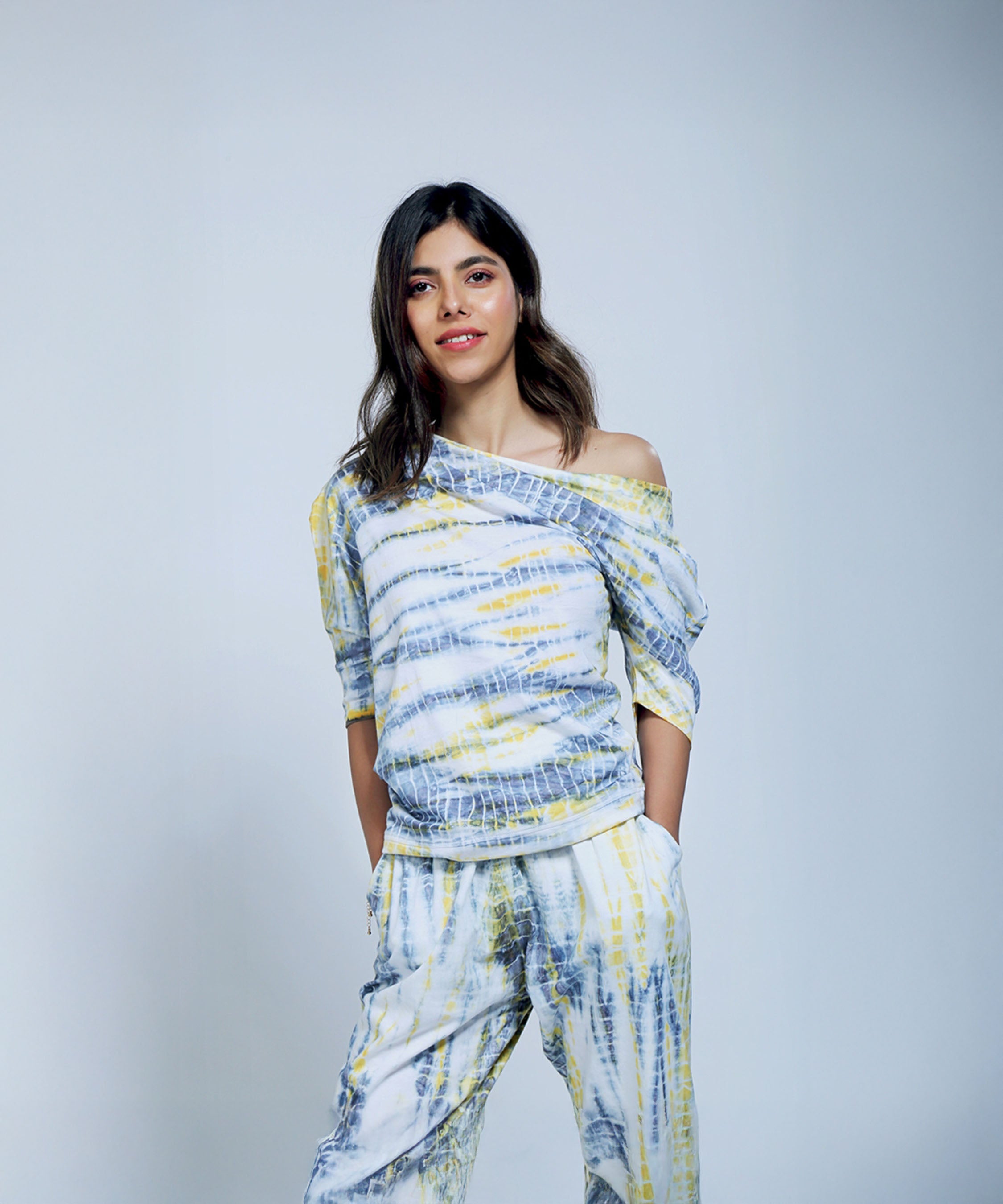 Woman modeling the One Side Off-Shoulder + Yoga Pants set in Yellow & Grey, made from organic cotton, against a plain light background.