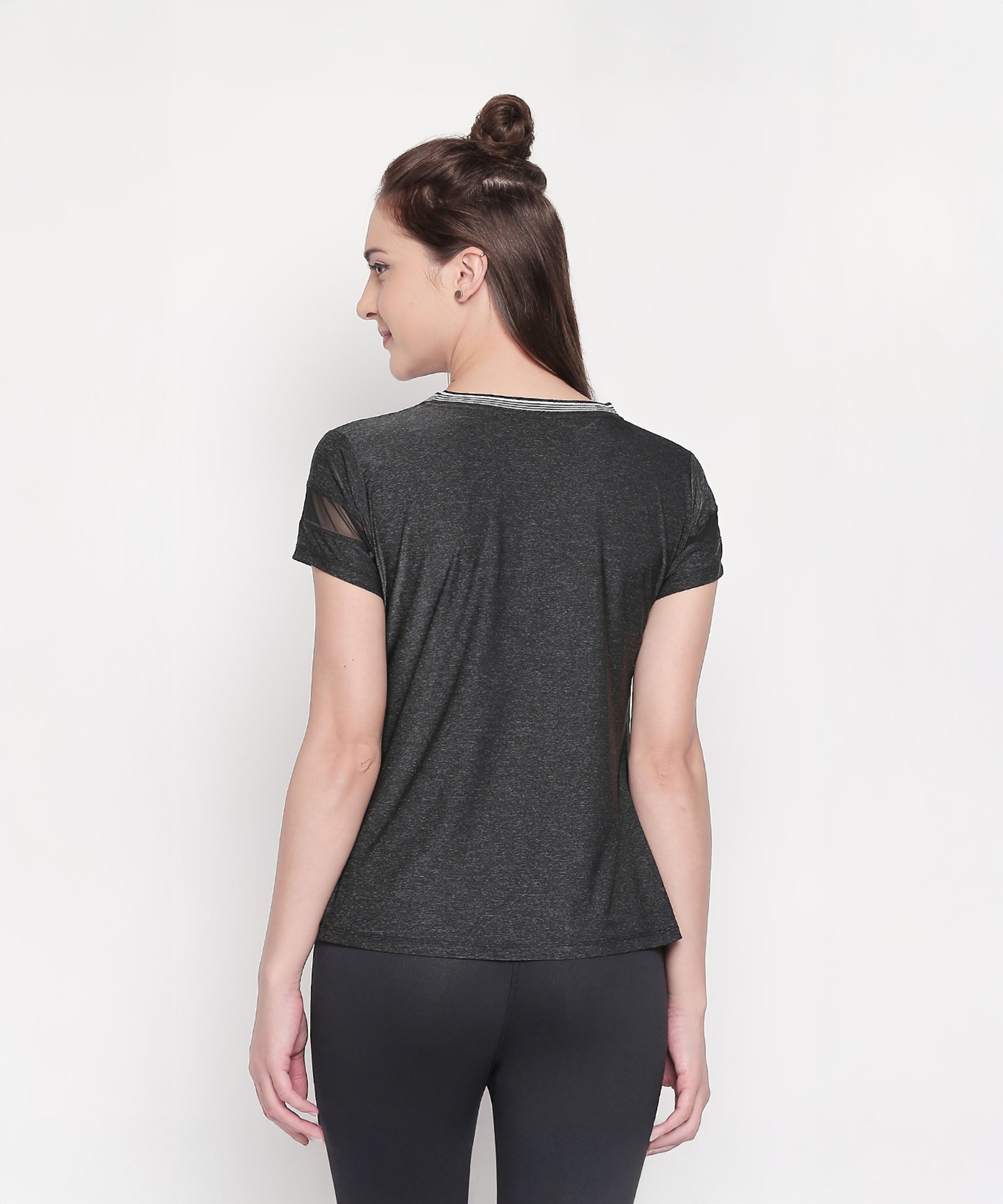 Woman with brown hair in a half-bun, facing away, wearing the Active Wear Top in Grey Color for Women and black leggings.