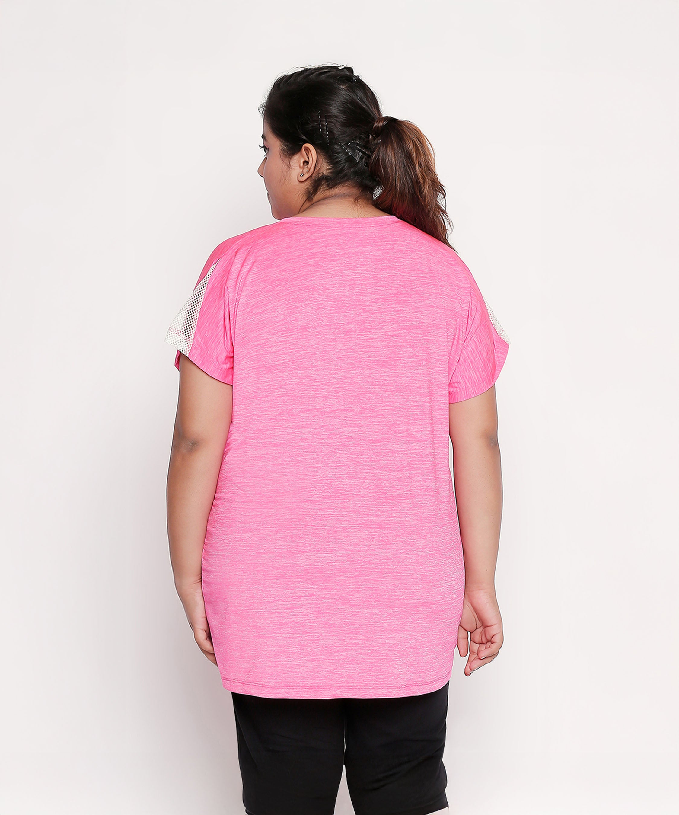 A woman, seen from behind, wears the Nova Sports Tee—a pink, short-sleeve performance top—paired with black pants, ideal for any workout wardrobe.