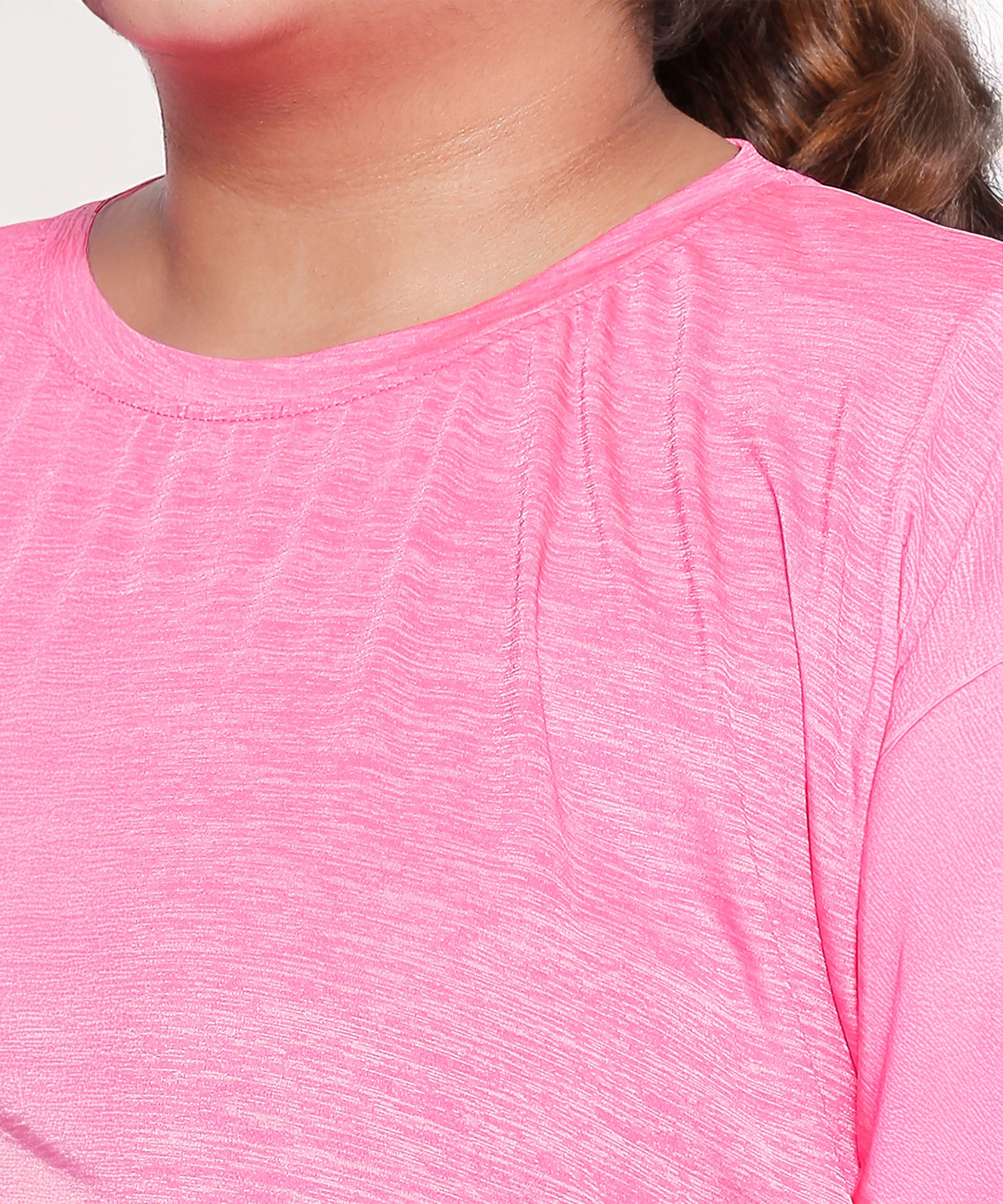Wearing the Nova Sports Tee—a bright pink, textured athletic top with a round neckline—adds energy to any workout wardrobe.