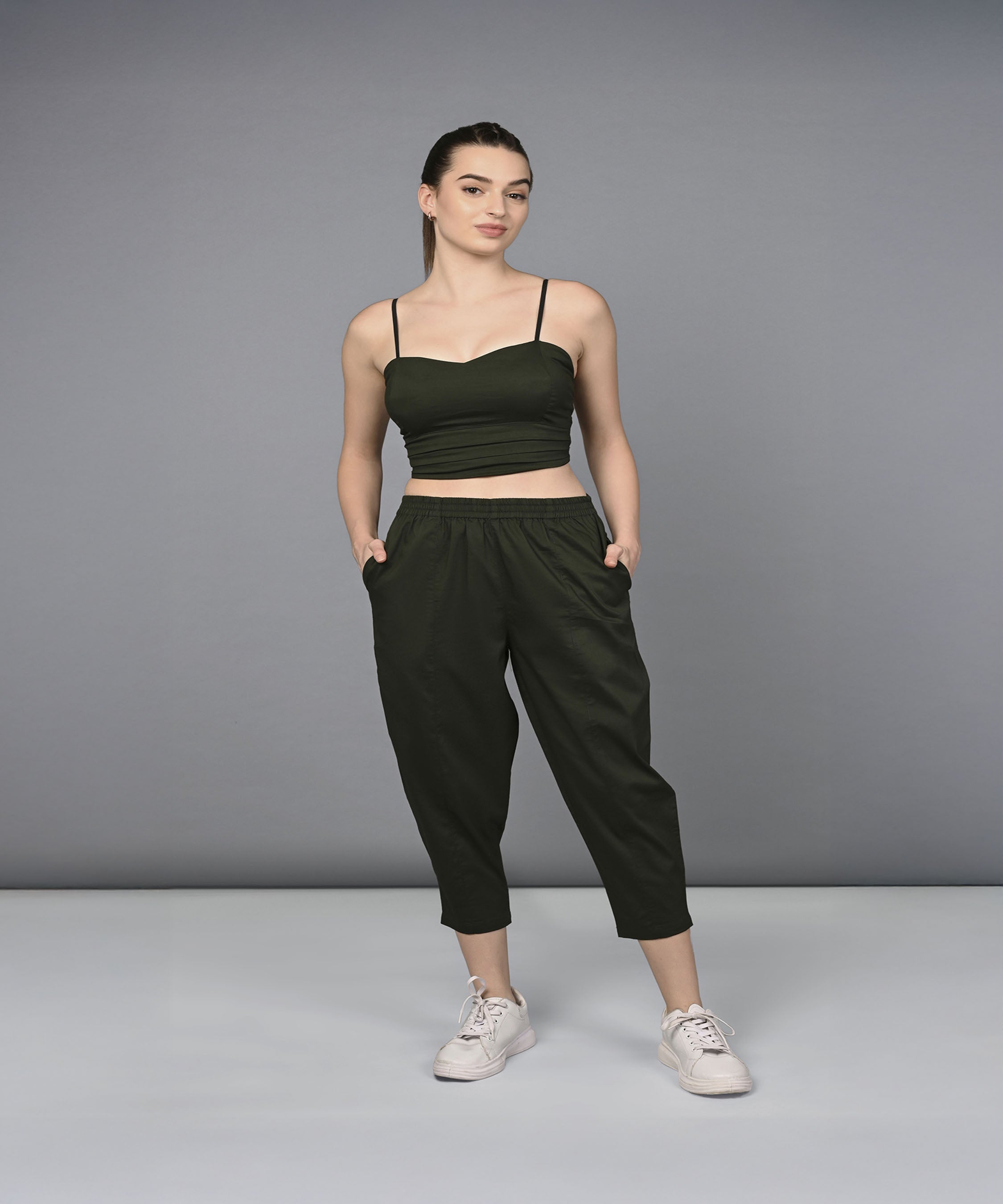 A woman models the Military Green Open Jacket & Yoga Pants with Bustiere set, standing with hands in pockets against a plain gray background.