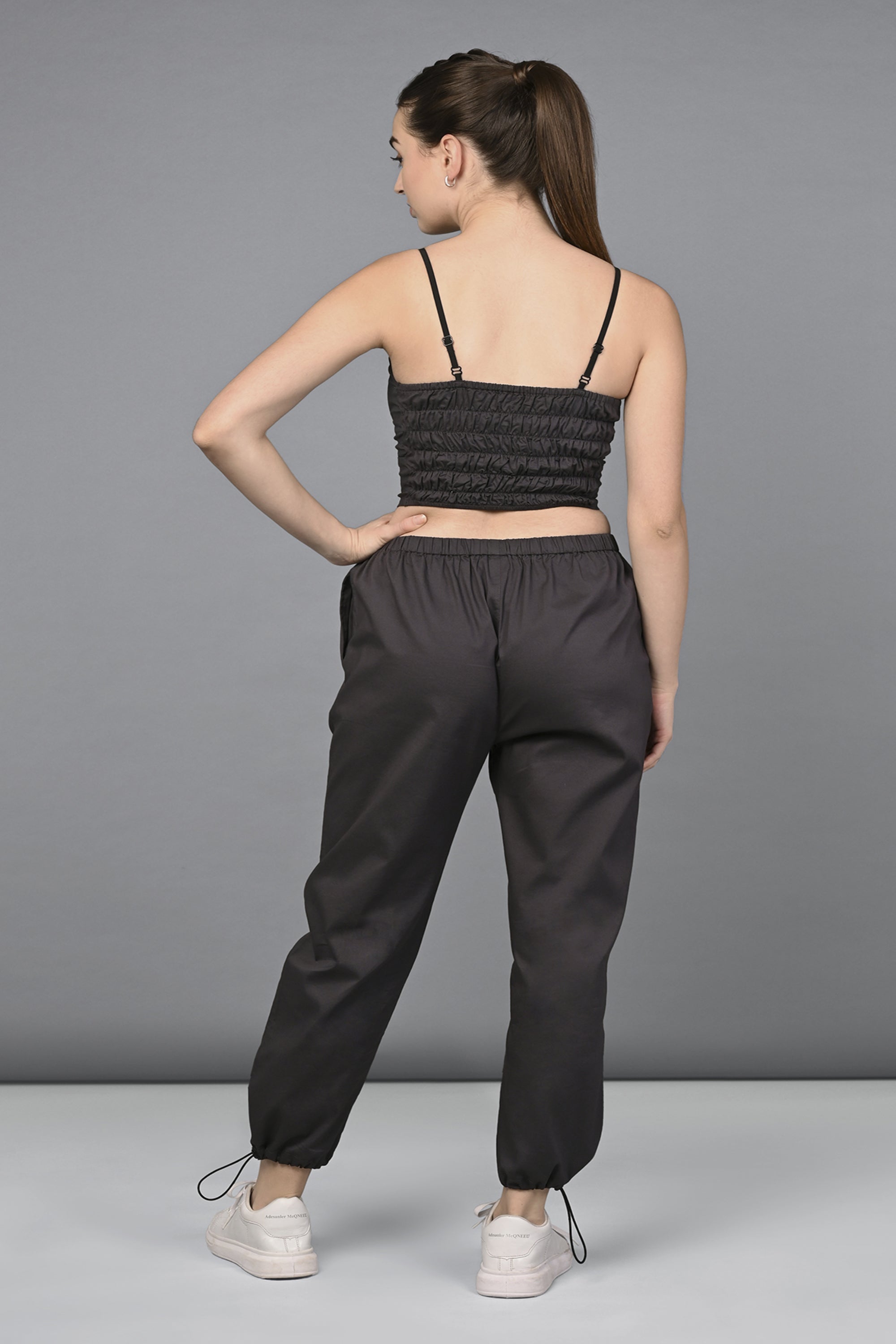 A woman stands with her back to the camera, wearing the Athleisure Blazer Tracks Two Piece Co-ord set in black and white sneakers.