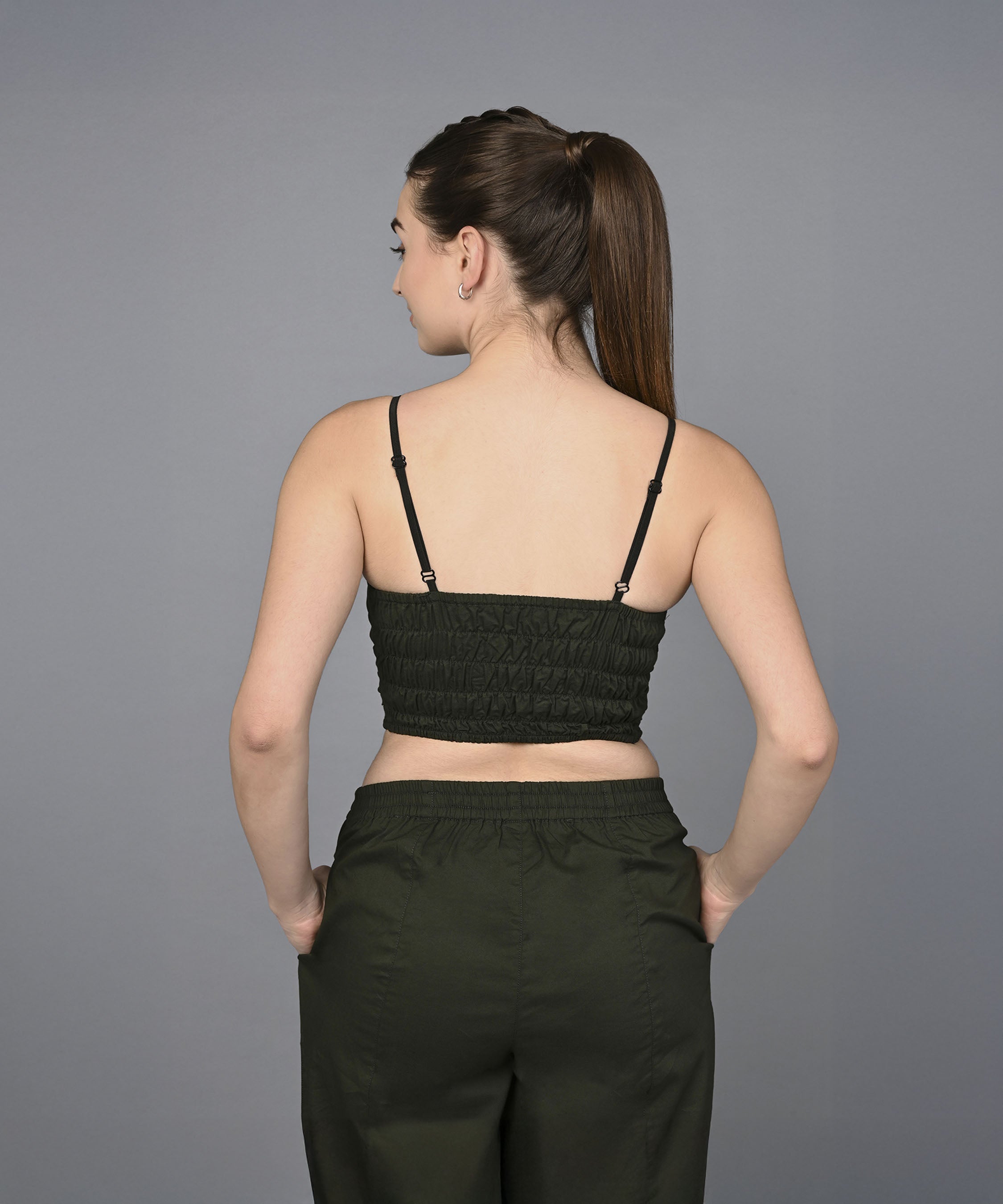 Woman with a high ponytail, seen from behind, wearing the Military Green Open Jacket & Yoga Pants with Bustiere set.
