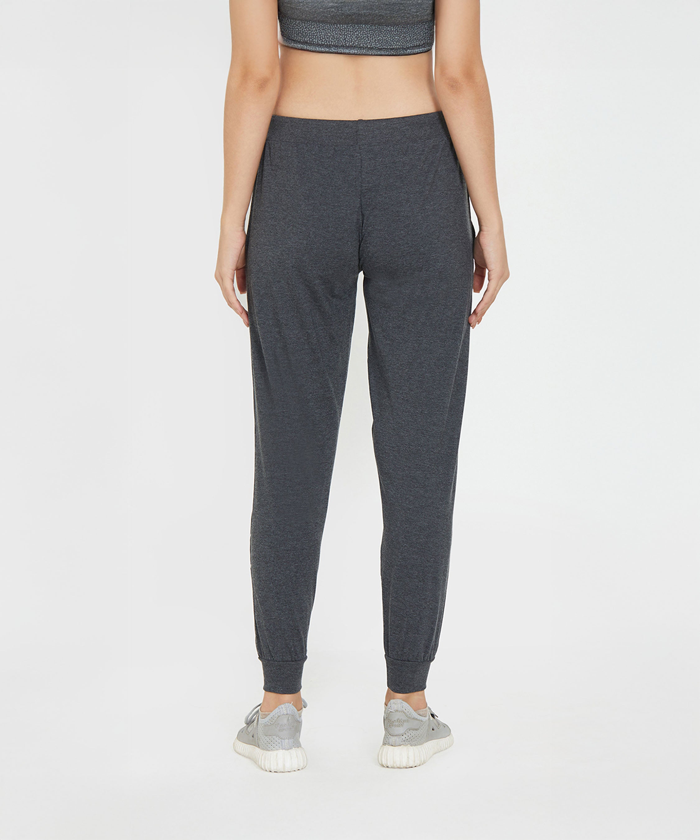 A woman is shown from the back, standing against a white background, wearing Joggers - Ashtanga Series Grey and sneakers.