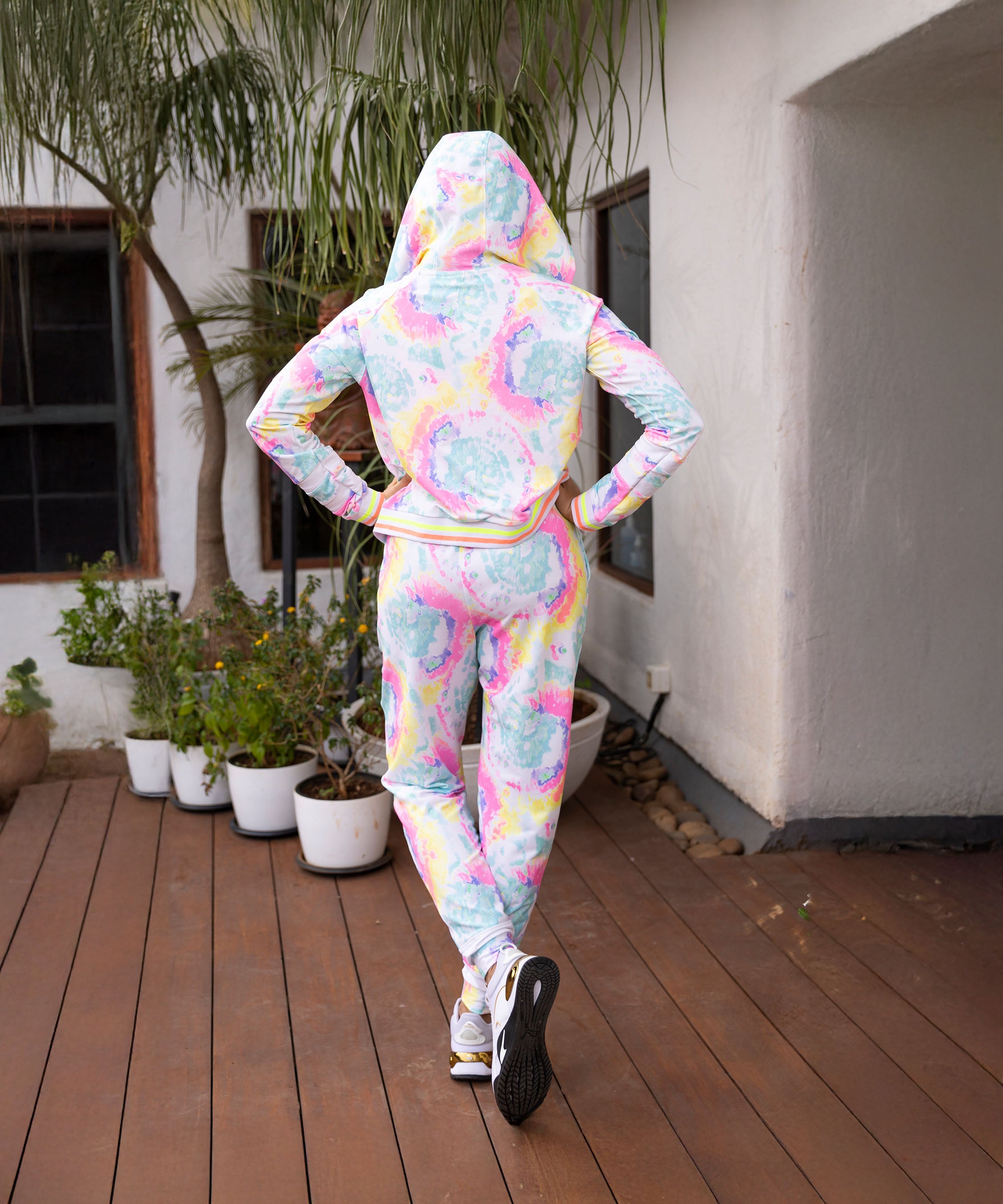 A person wearing the Multicolour Neon Jacket & Joggers Set with cargo pockets stands on a wooden deck facing away, near potted plants.