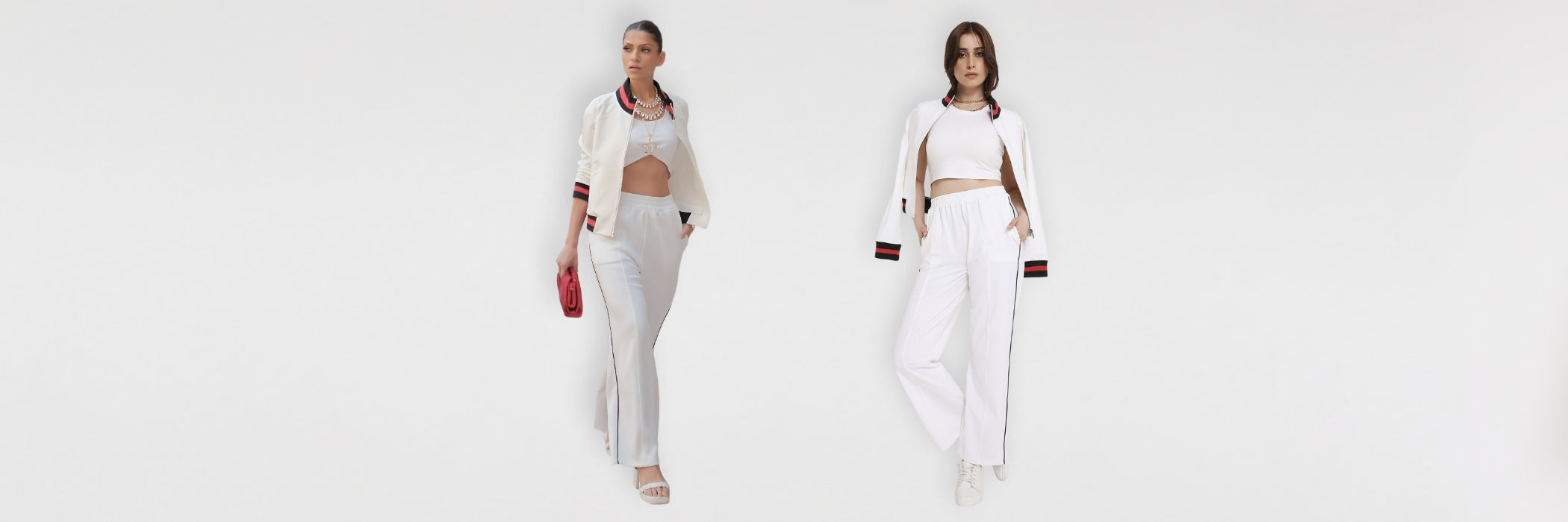 Two women in white outfits and long jackets stand against a plain white background.