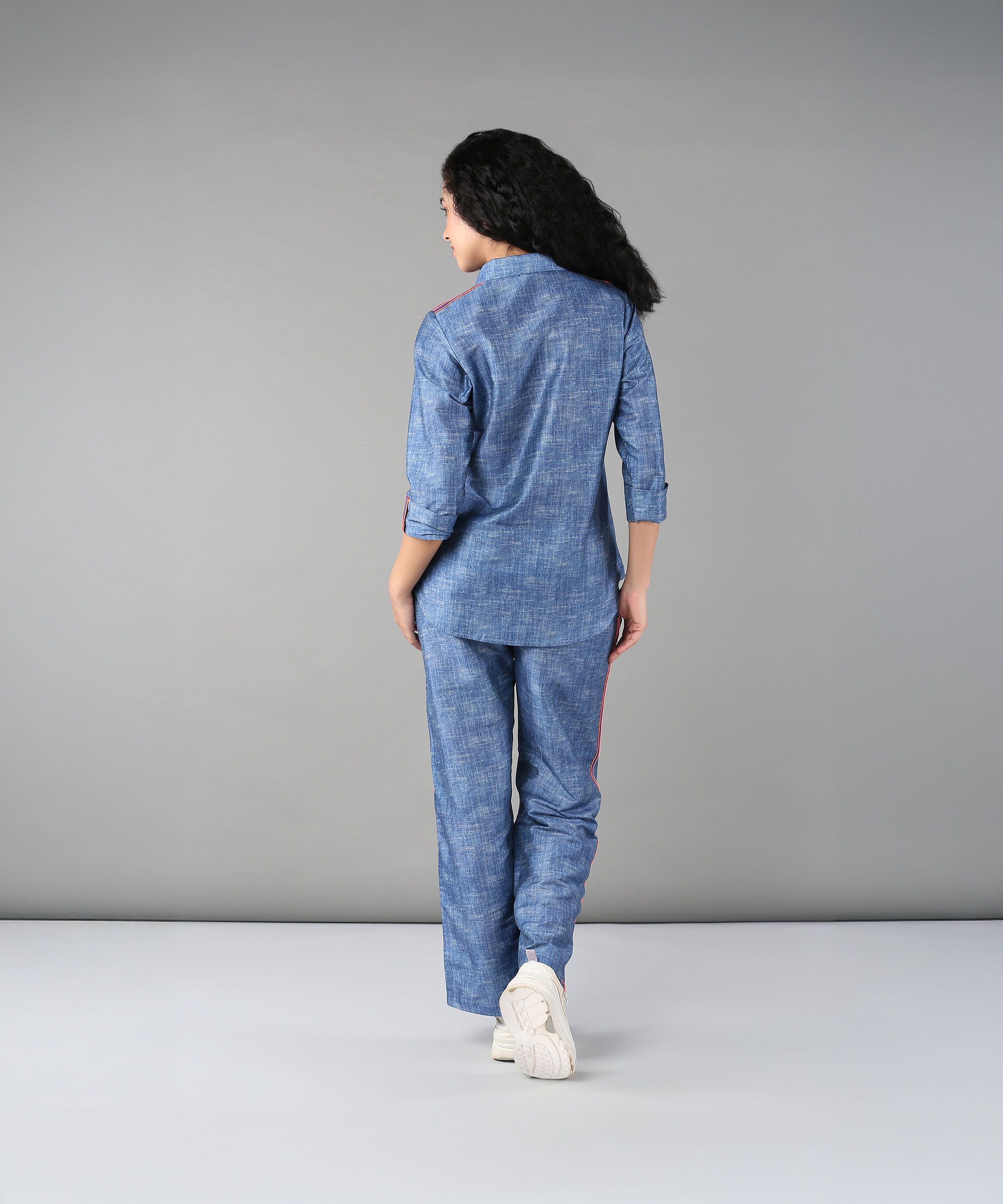 A woman stands with her back to the camera in a Denim Linen Co-Ord Set, featuring a relaxed fit shirt and matching pants, set against a plain gray background.