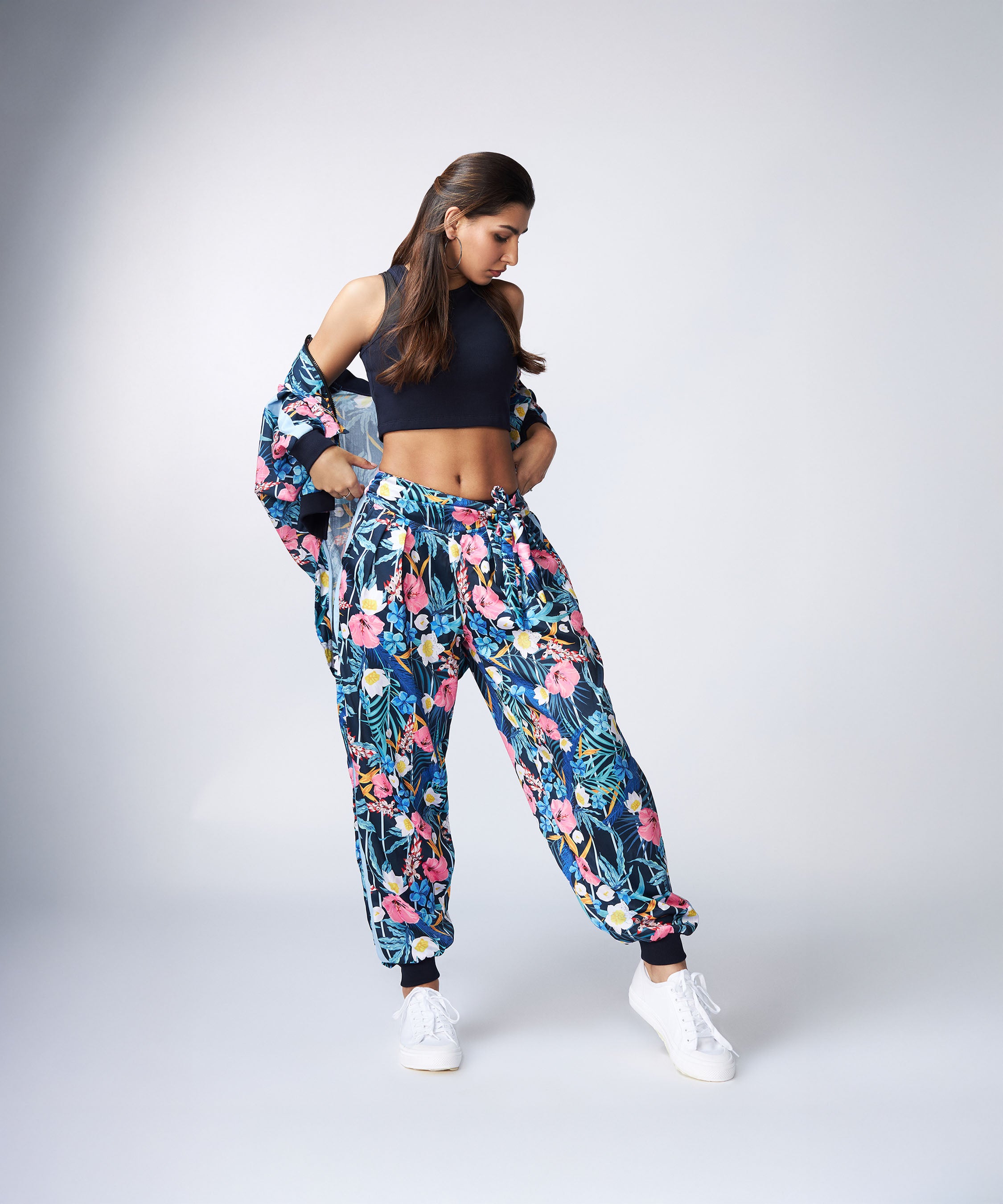 Woman in the Tuna Active Floral Co-ord Set, paired with a black crop top and white sneakers, standing against a plain background.
