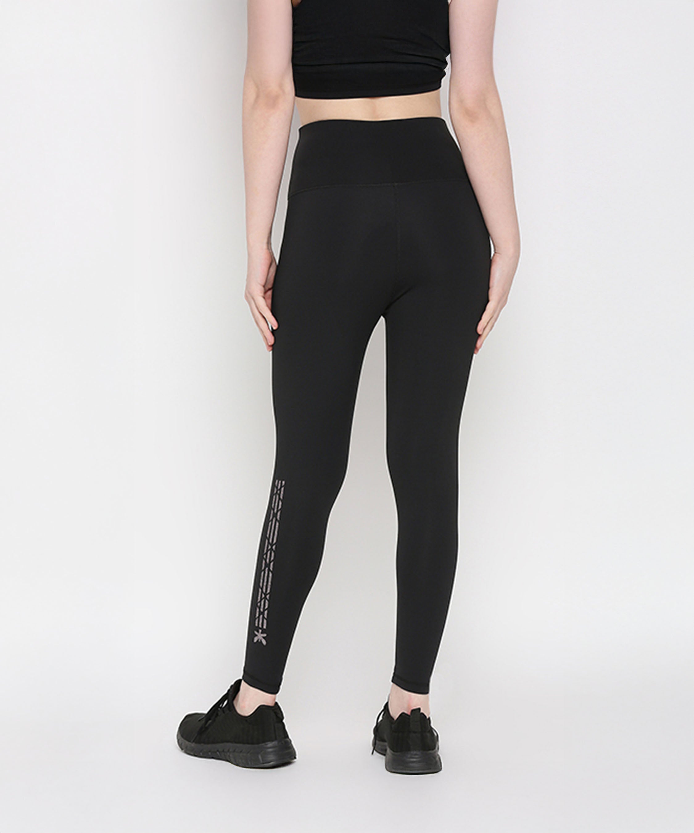 Person in Tuna Active Black Leggings With Print, facing away from the camera; stretchy workout pants feature a design on the lower leg.