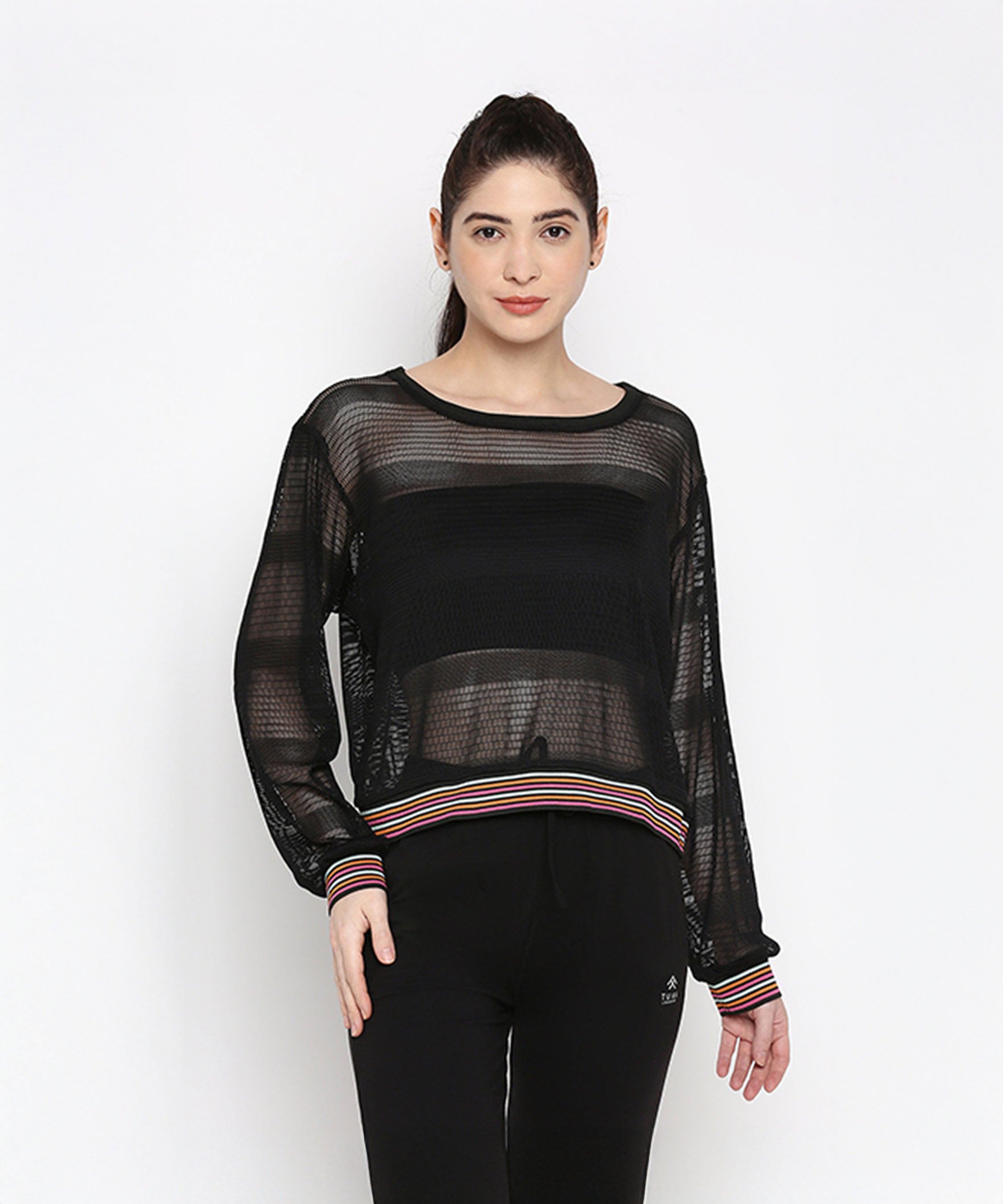 A woman models the Black Netted Top with striped cuffs, paired with black pants for a sporty look against a white background.
