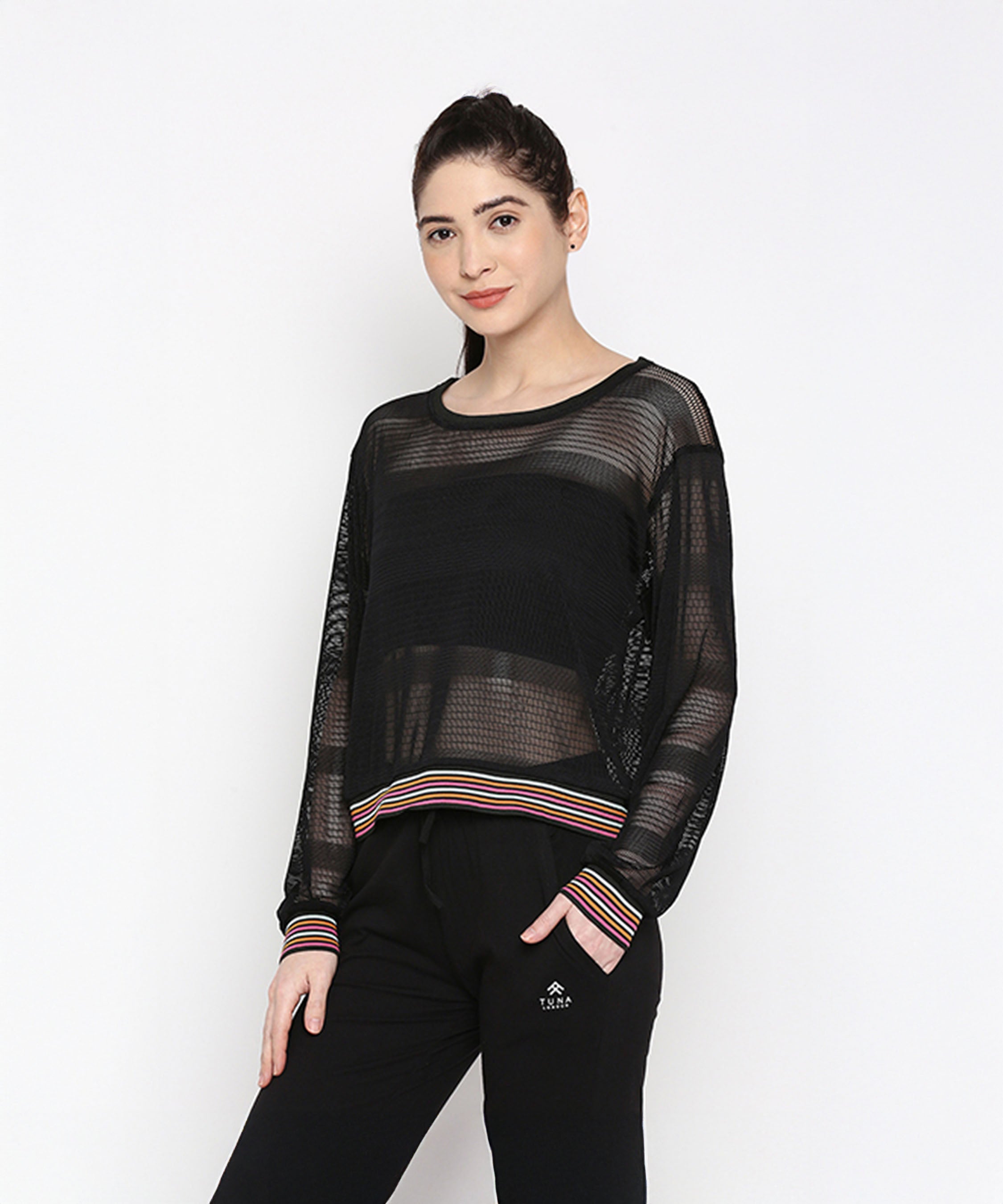 A woman wears the Black Netted Top with black pants, posing against a plain white background for a sporty look.