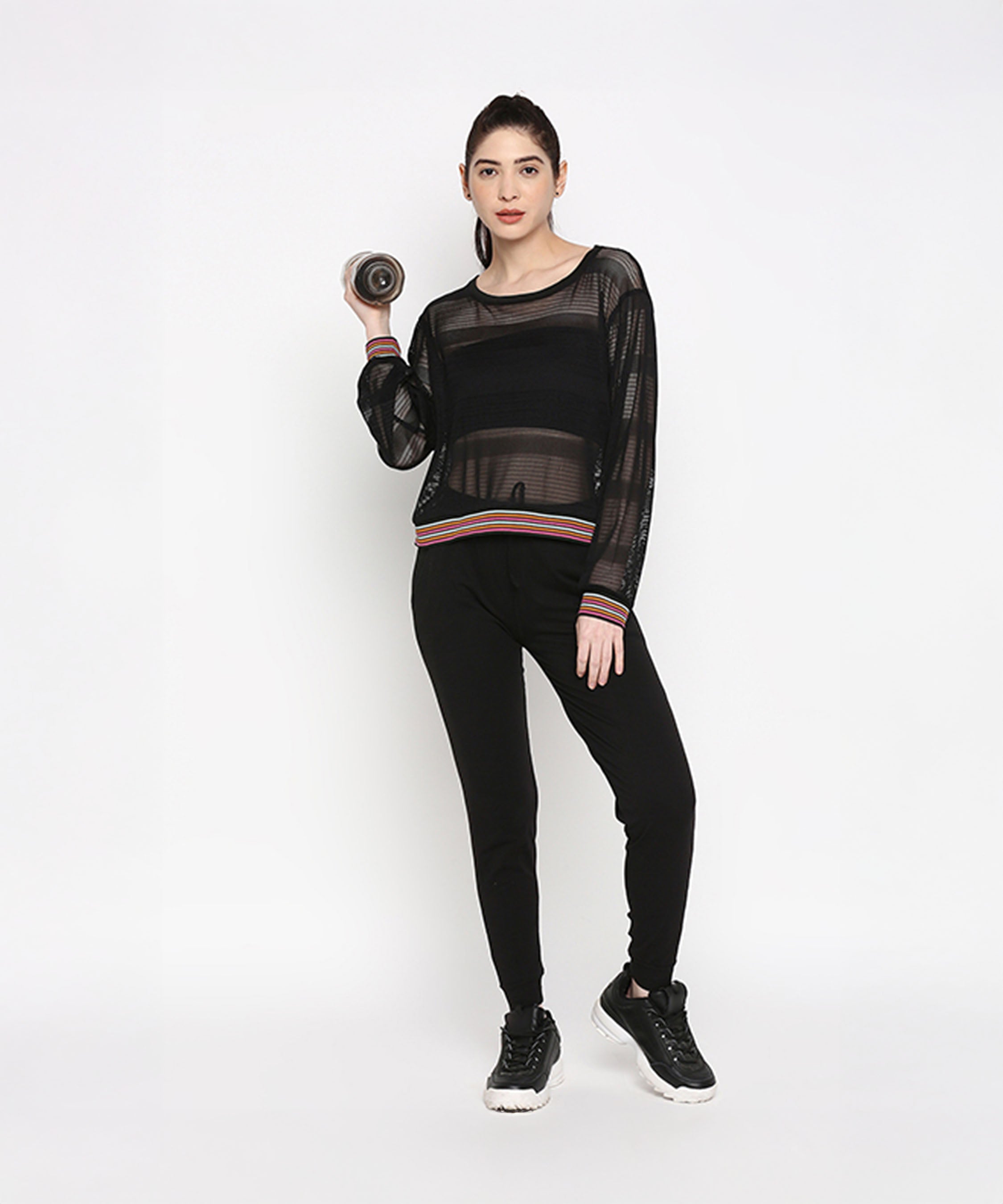 A woman showcases the Black Netted Top, paired with leggings and holding a dumbbell, striking a sporty pose against a plain white background.