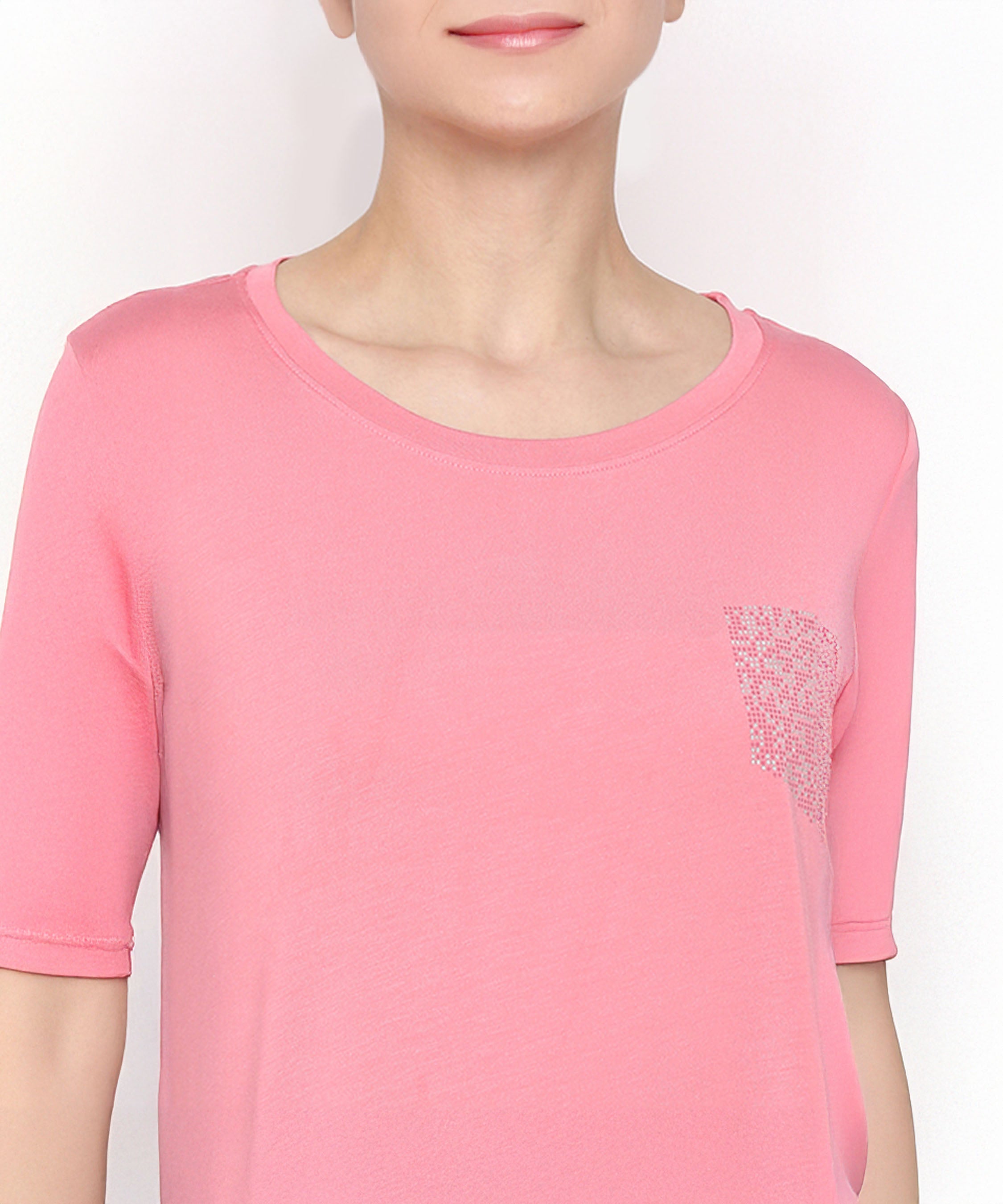 Wearing the Coral Blissful Tulip Set, a coral pink cotton modal top featuring a small textured pocket, shown from shoulders to upper chest.
