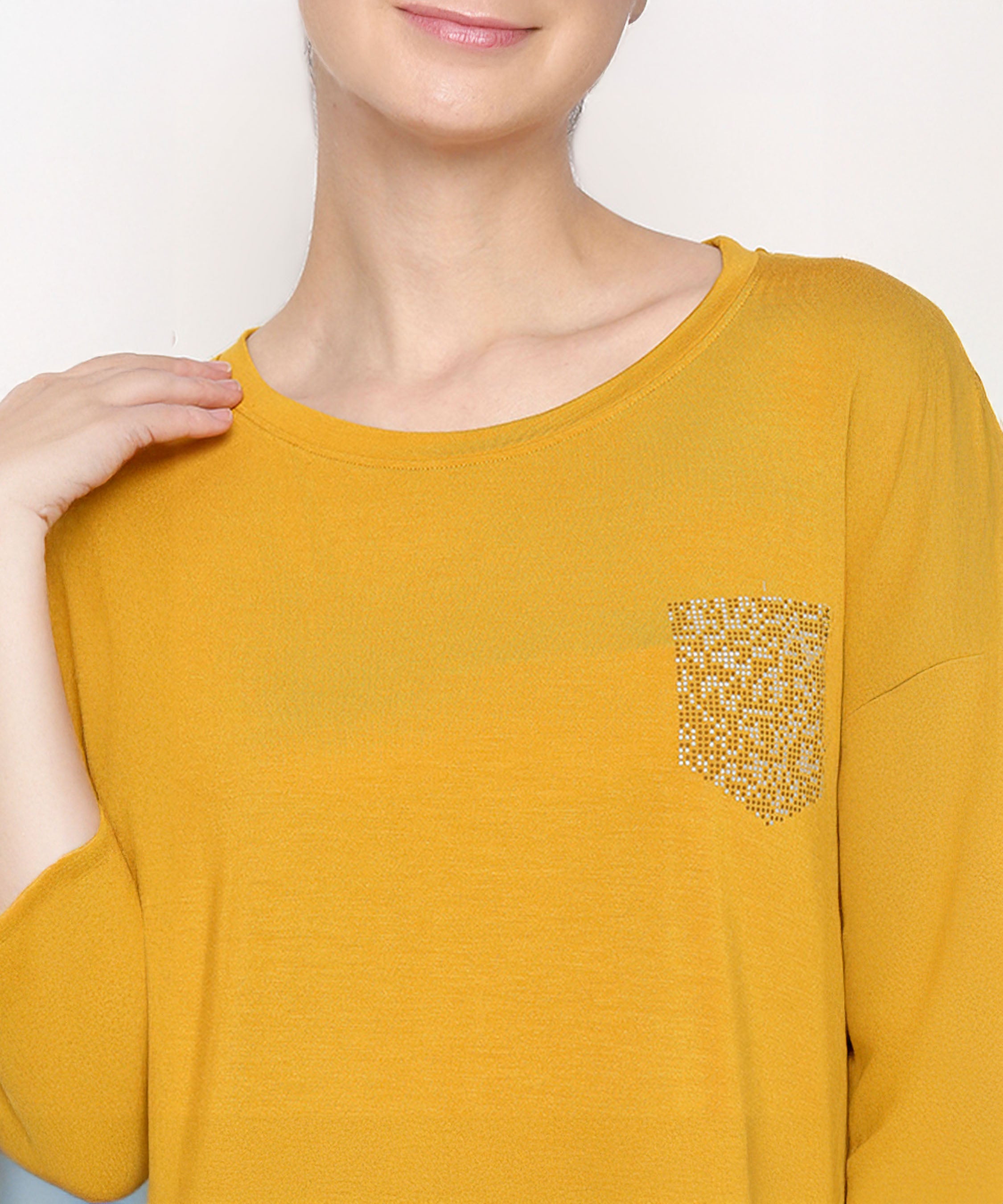 A person wears the Mustard Chic Set, featuring a mustard yellow top with a sequined pocket and soft, elasticated waistband cotton modal trackpants, smiling slightly.