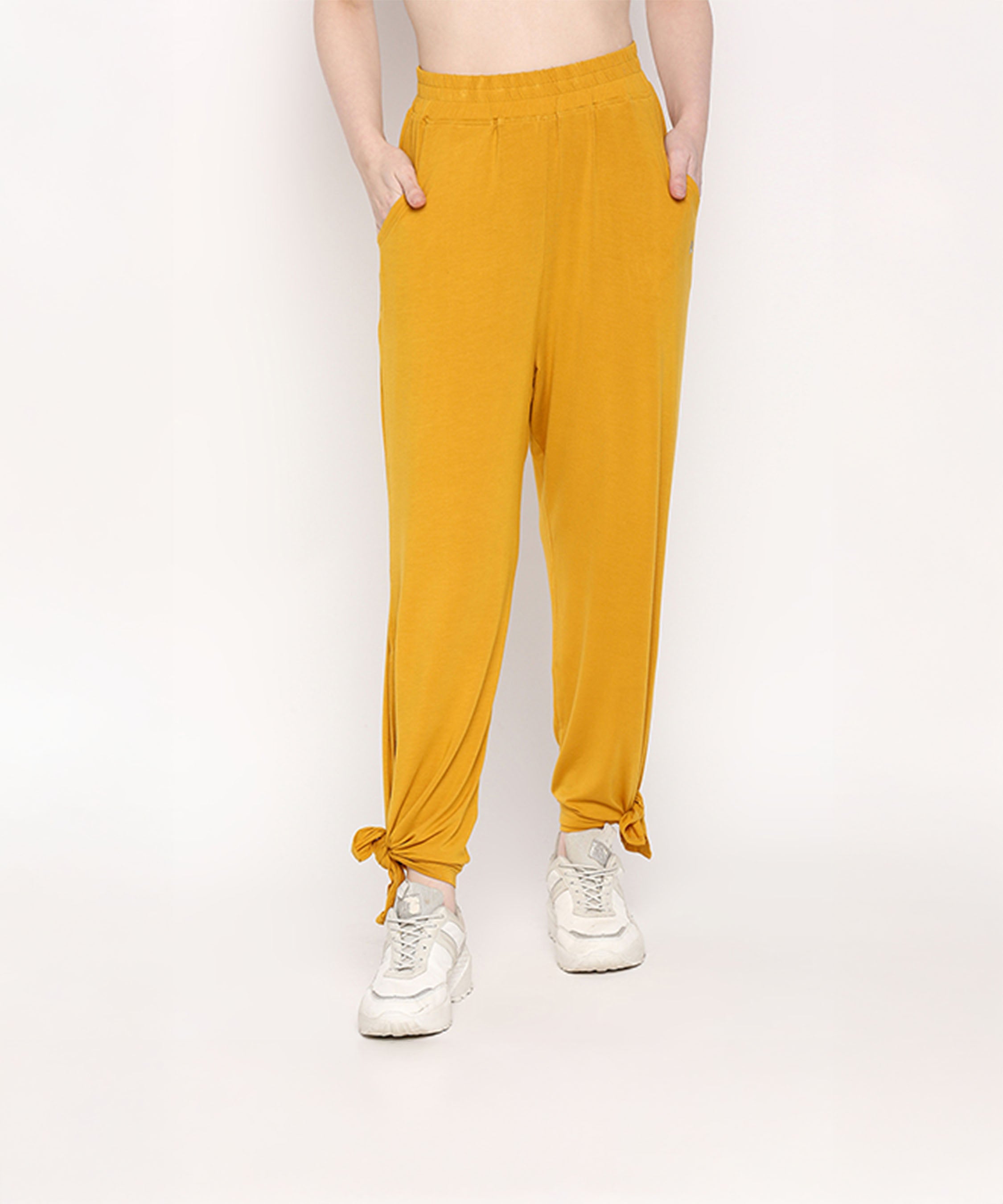 A person wearing the Mustard Chic Set, featuring mustard yellow Cotton Modal Trackpant joggers with a soft elasticated waistband and white sneakers, stands with hands in pockets.