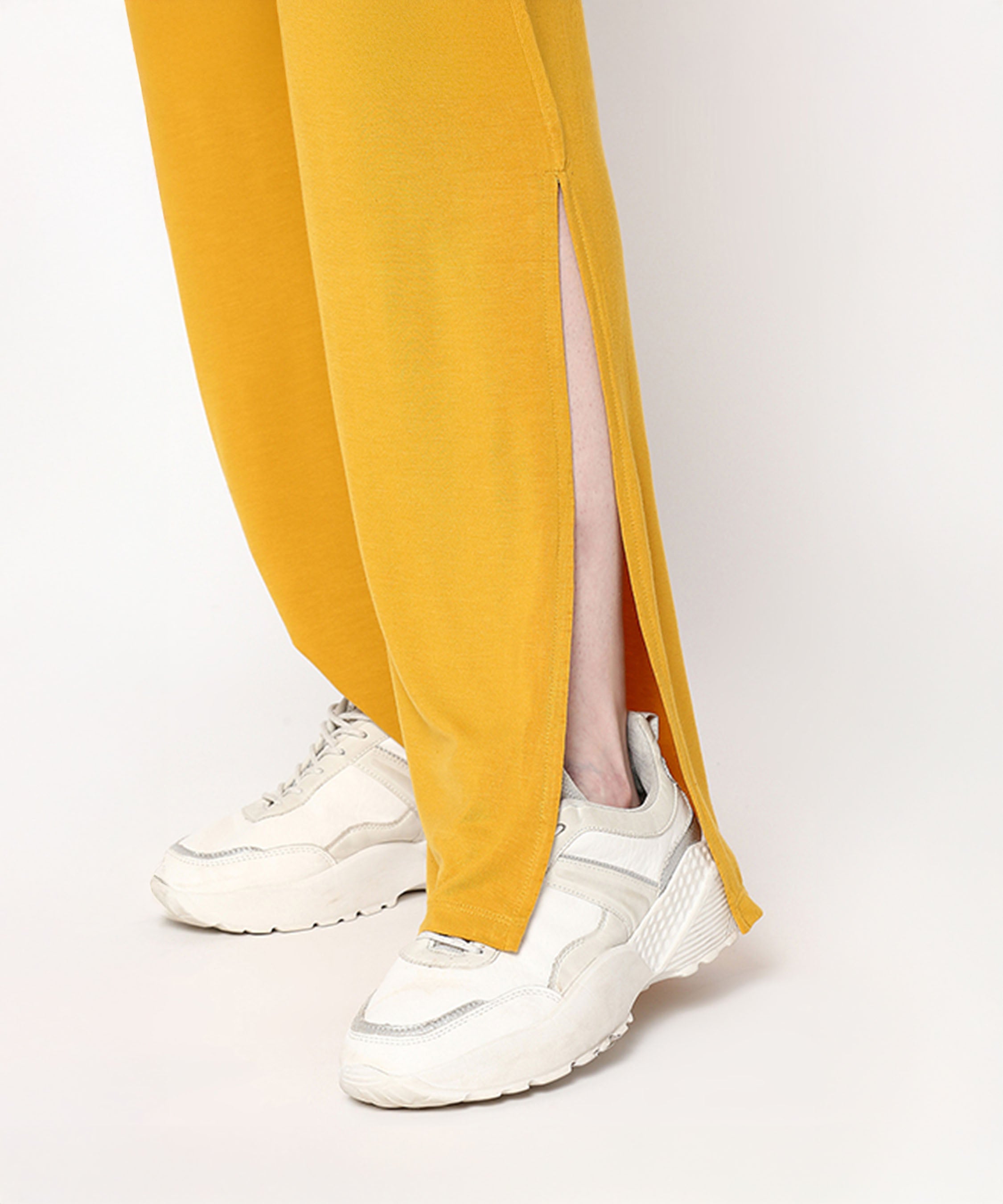 A person wearing the Mustard Chic Set—a mustard yellow top and cotton-modal trackpant with a soft elasticated waistband—paired with white sneakers.