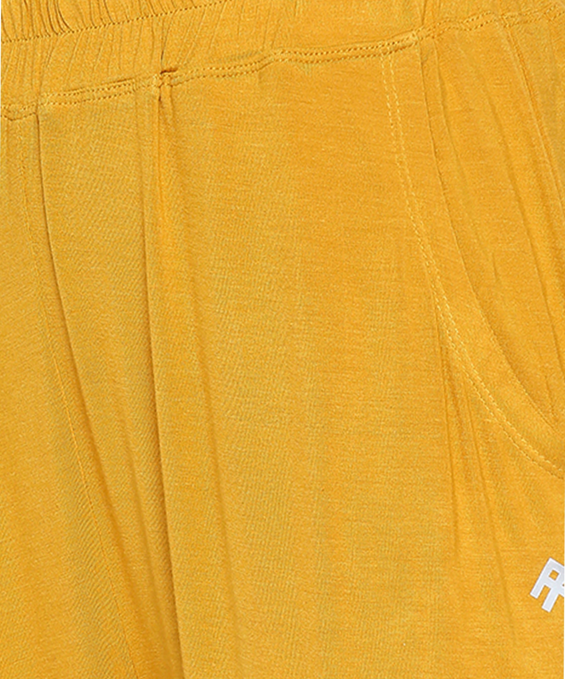 Close-up of the Mustard Chic Set trackpant in yellow, featuring a pocket and elastic waistband.