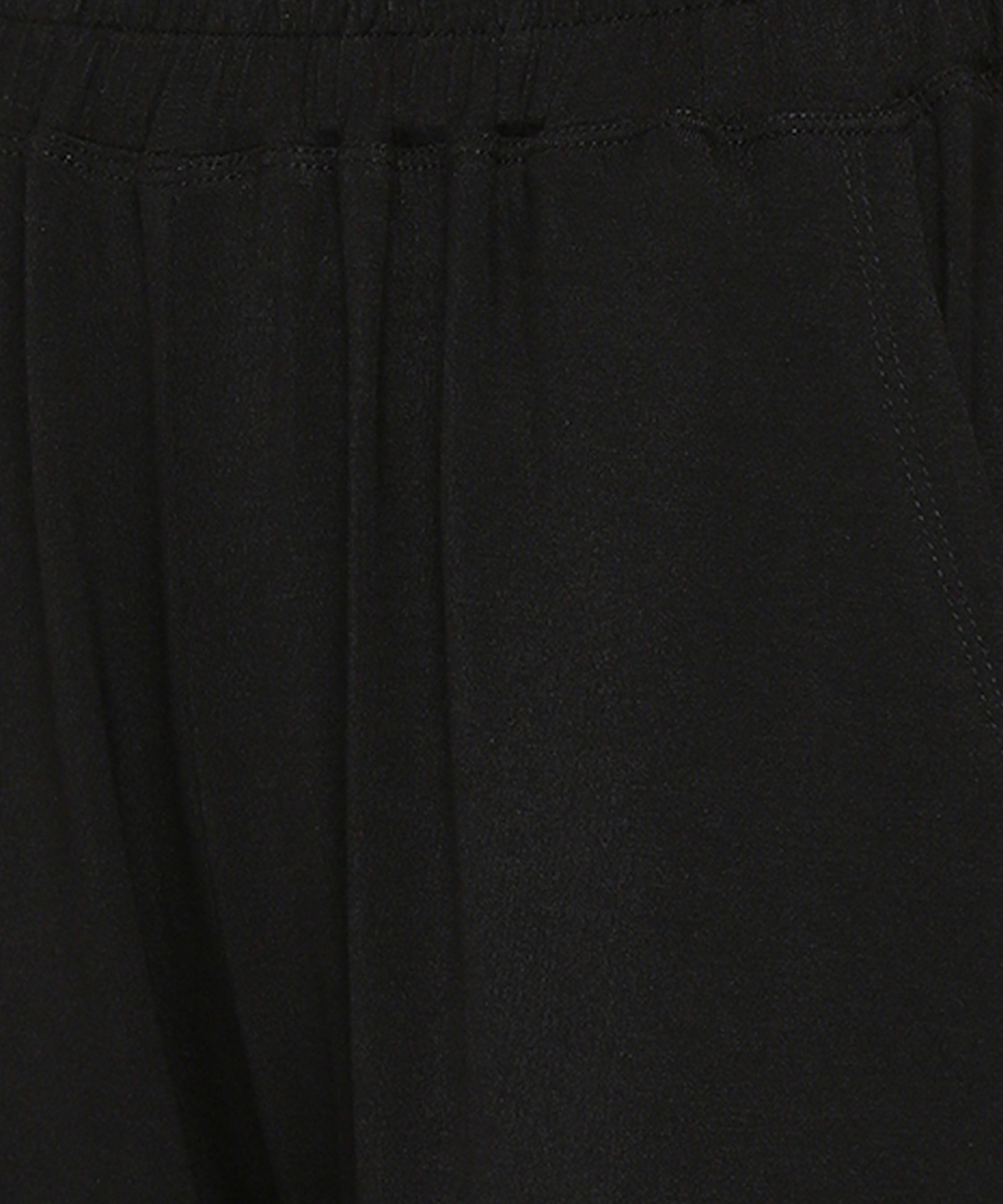Close-up of the Comfy Black Set with Side Sparkle showing its black, loose fit track pant fabric, elastic waistband, and visible stitching by the pocket.