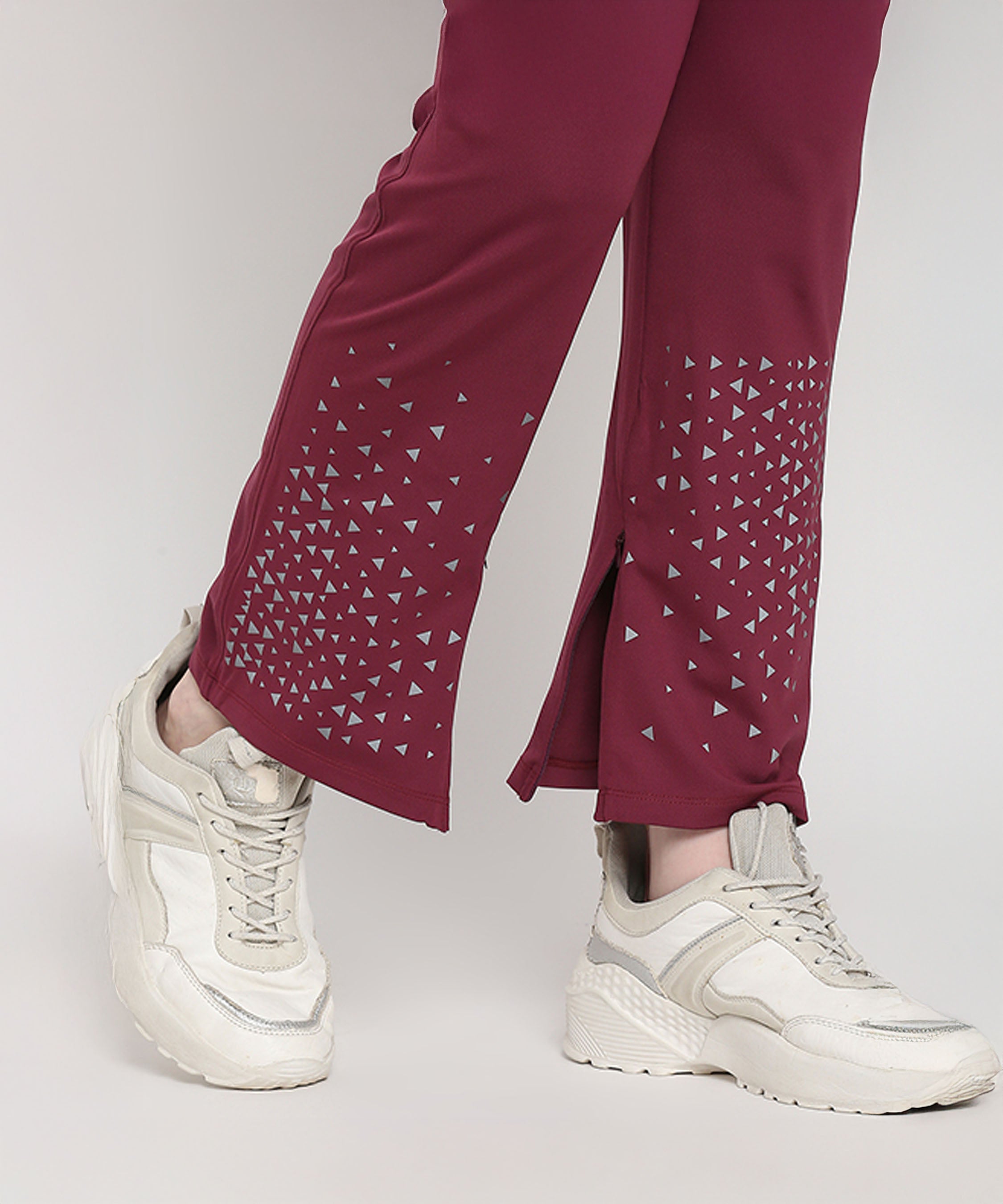 Model wears Tuna Active Wine Color Boot Cut Pants featuring small triangle patterns with white sneakers, standing against a light background.