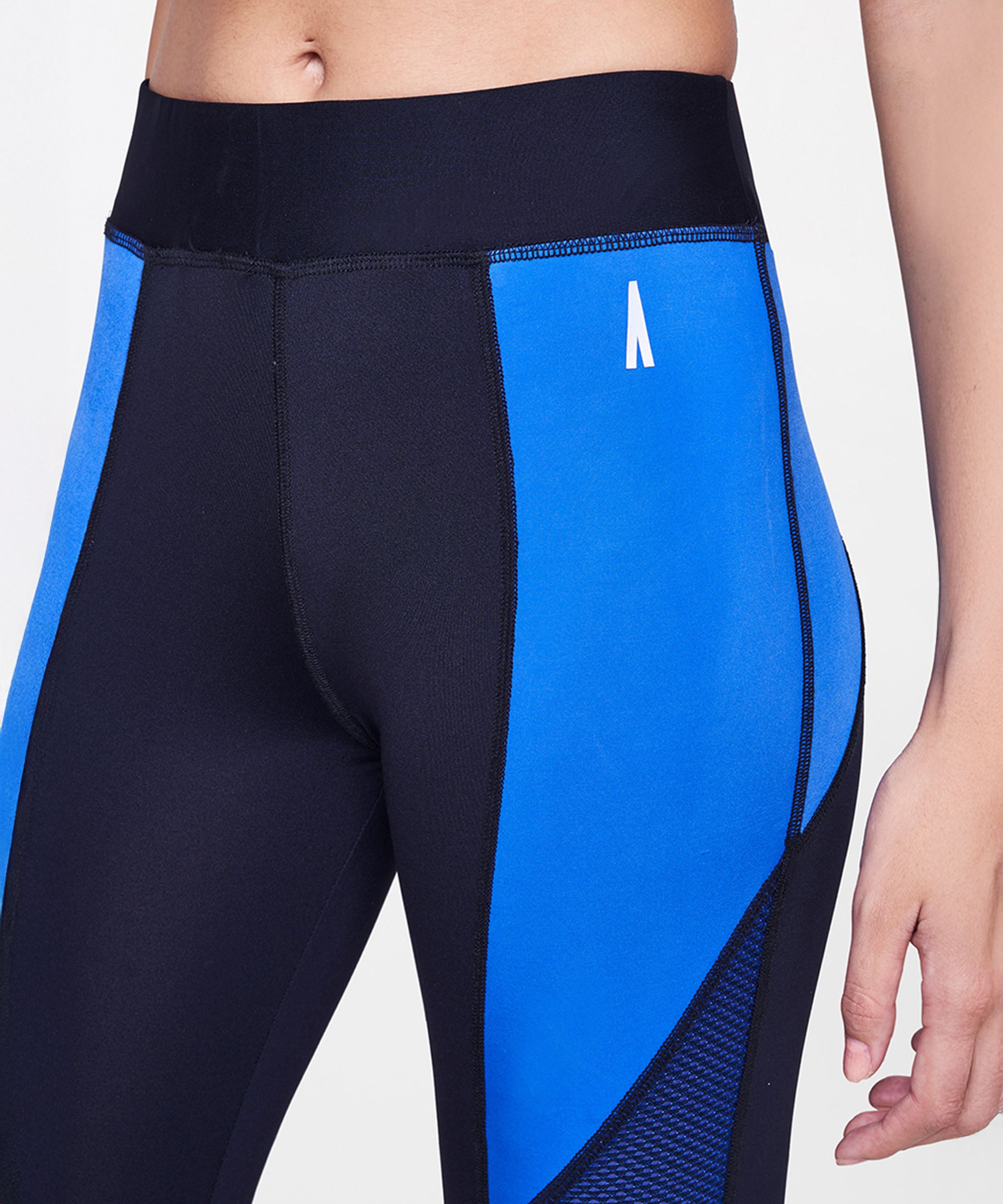 Close-up of a person wearing Indigo Leggings, deep blue in color, featuring a small white logo on the hip.
