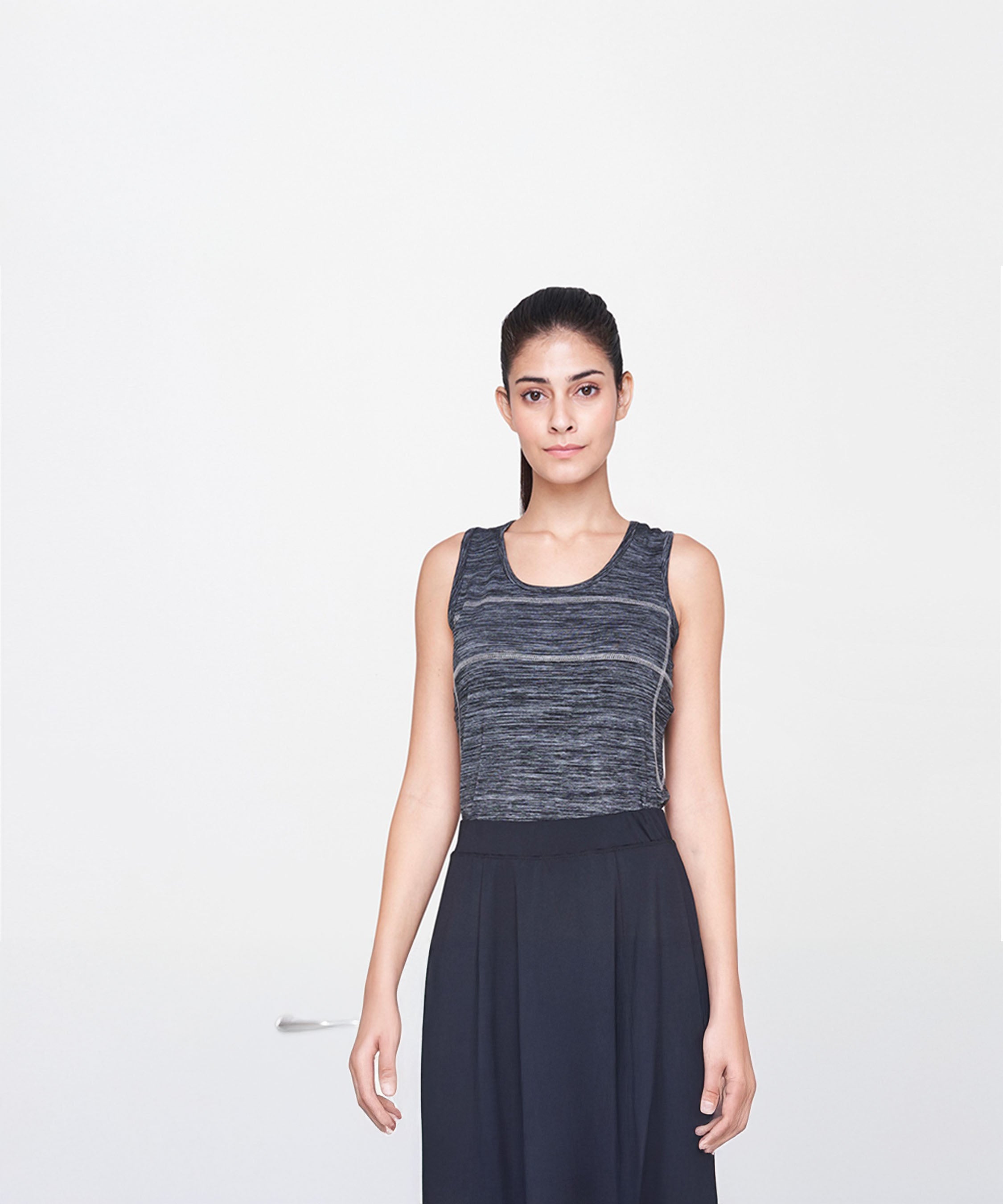 A woman models the Grey Tank Top in a relaxed fit with a black skirt, standing against a plain white background to highlight casual style.