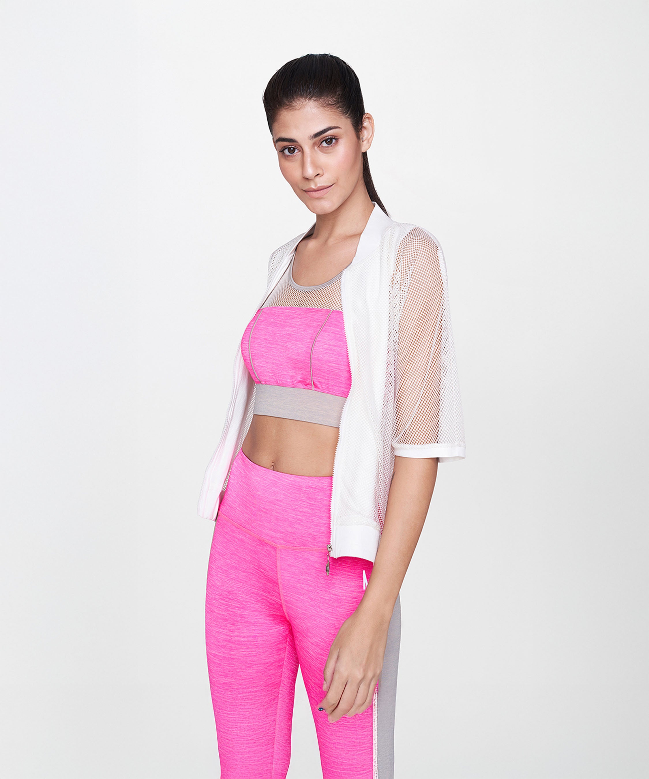Woman wearing pink athletic wear and a White Sheer Jacket stands against a plain white background.