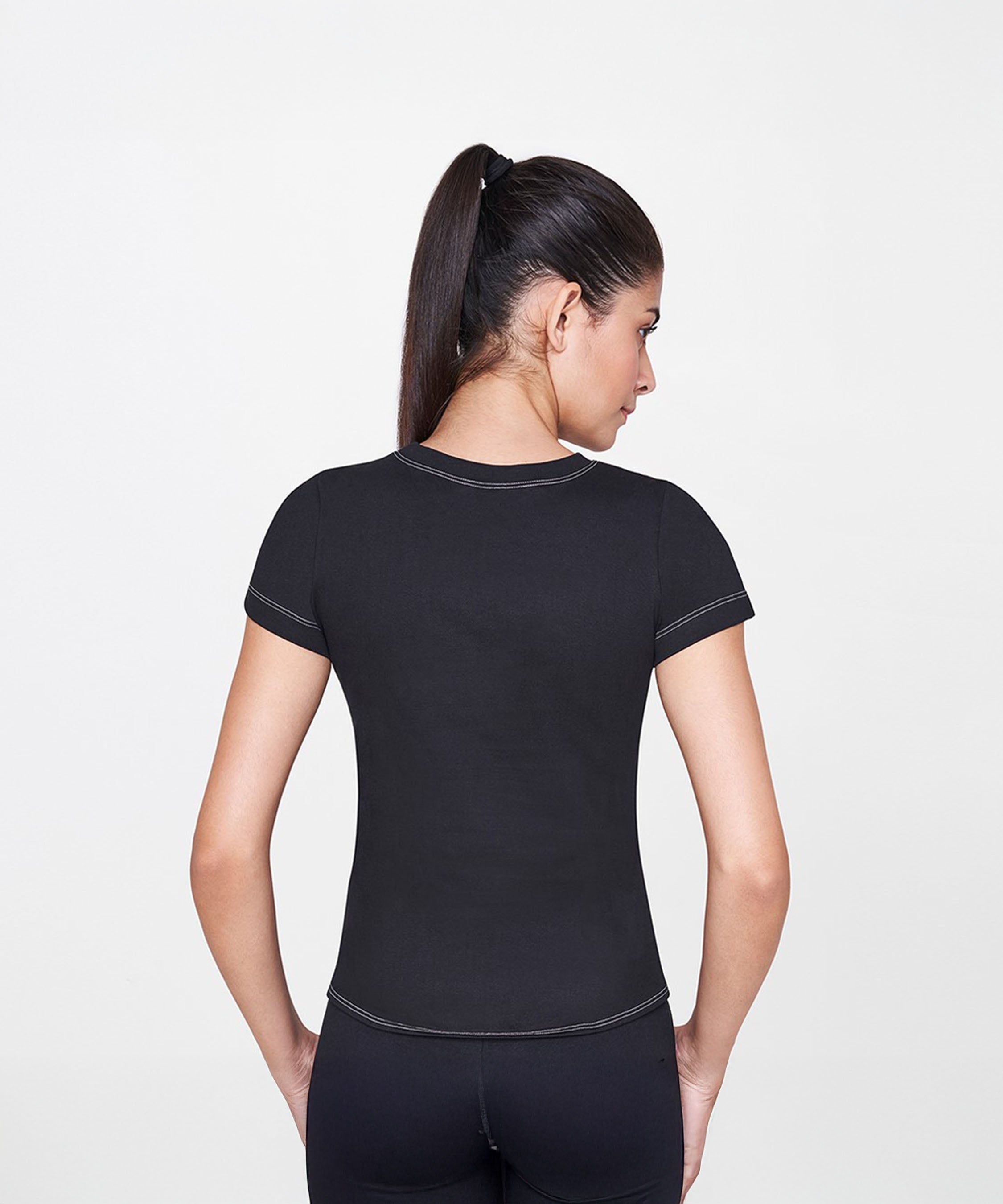 A woman with dark hair in a ponytail is seen from behind, wearing the Black T-Shirt—a fitted and timeless wardrobe staple.