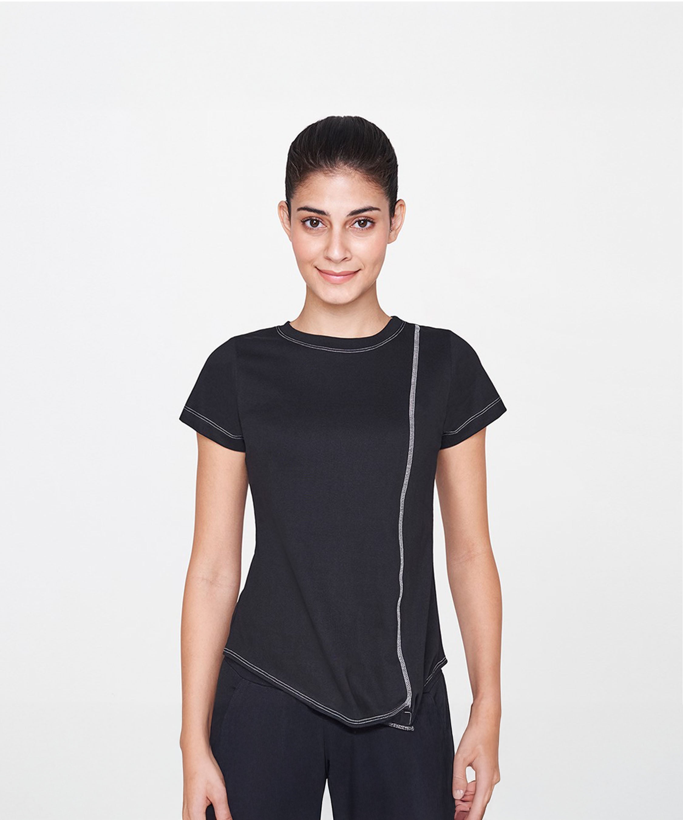 A woman with dark hair in a ponytail wears the Black T-Shirt with white stitching, smiling—an essential piece that adds classic style to any casual outfit.