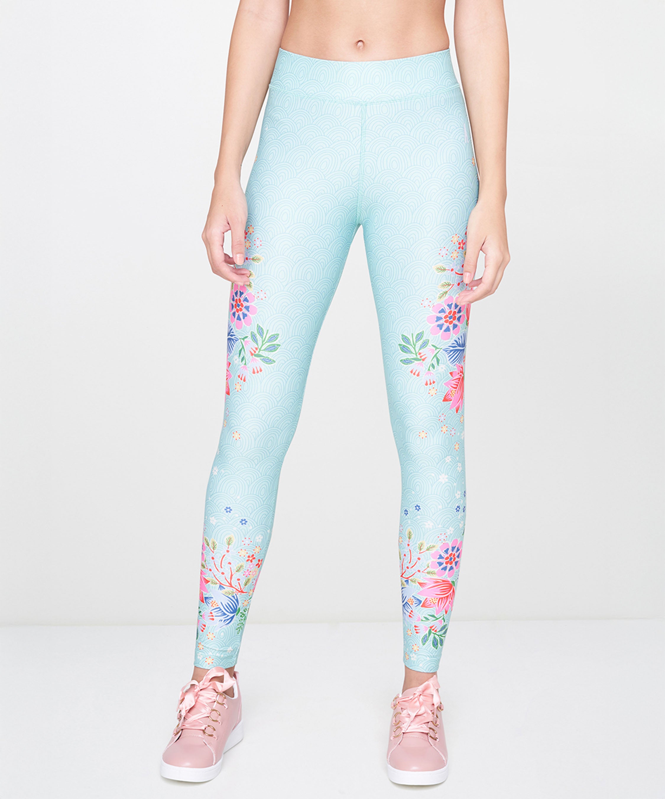 Model wears Aqua Printed Leggings and pink sneakers, standing against a plain white background.
