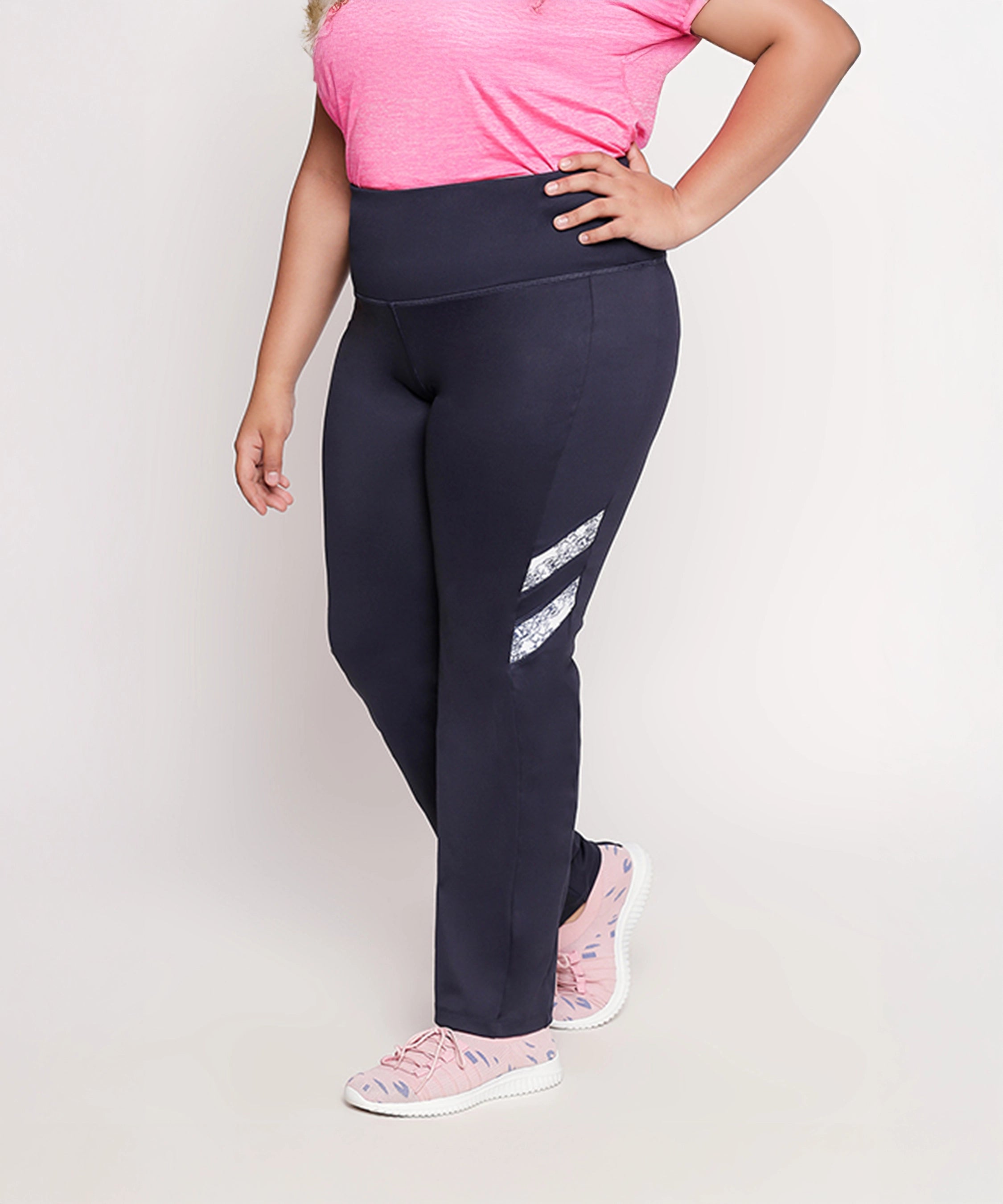 Person wearing a pink t-shirt, Tuna London Iris Navy Polyblend Track Pant for women, and pink sneakers, standing against a light background.