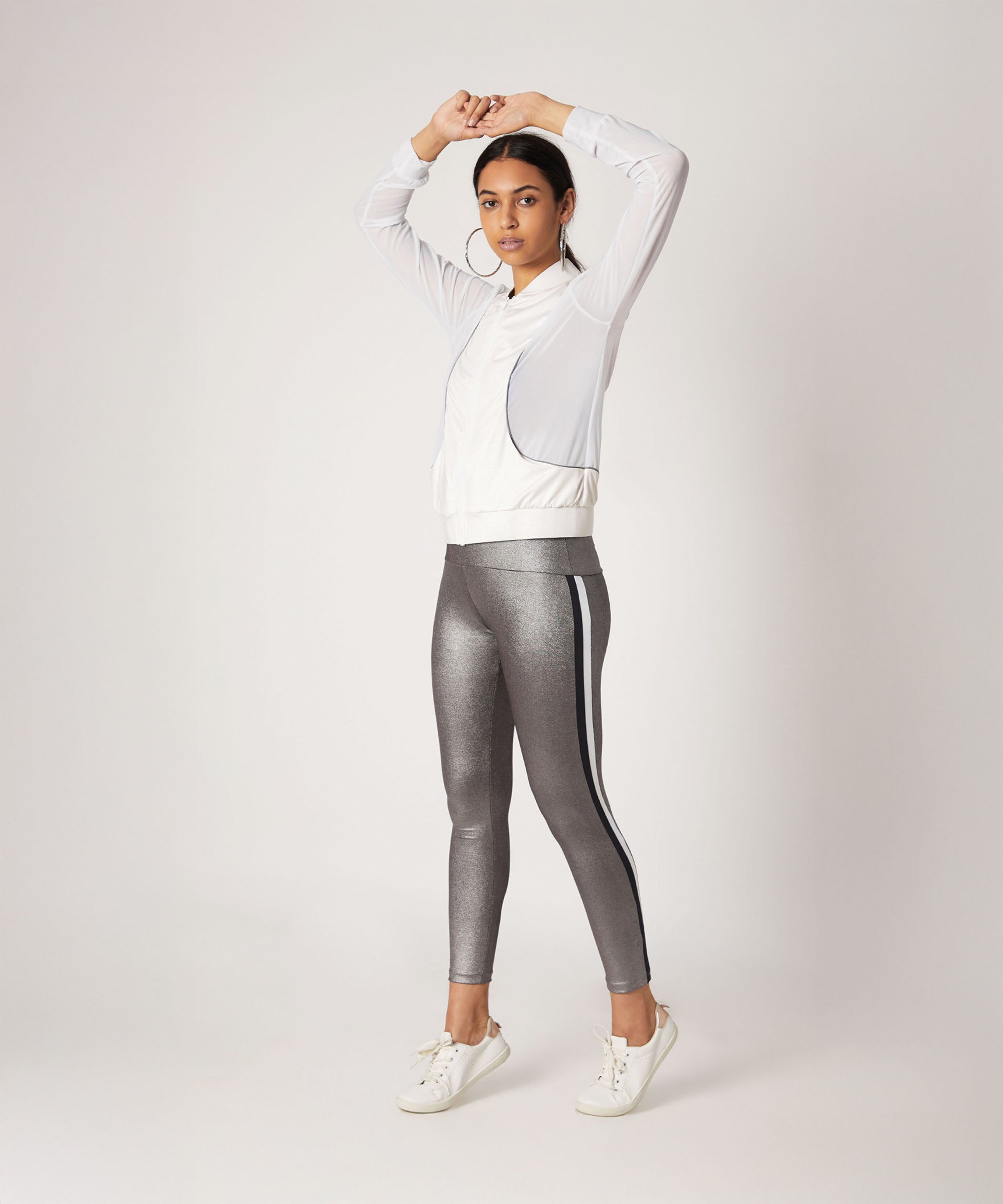 Woman in athletic wear poses with arms raised, wearing a white jacket and High Waisted Metallic Leggings TLC116.