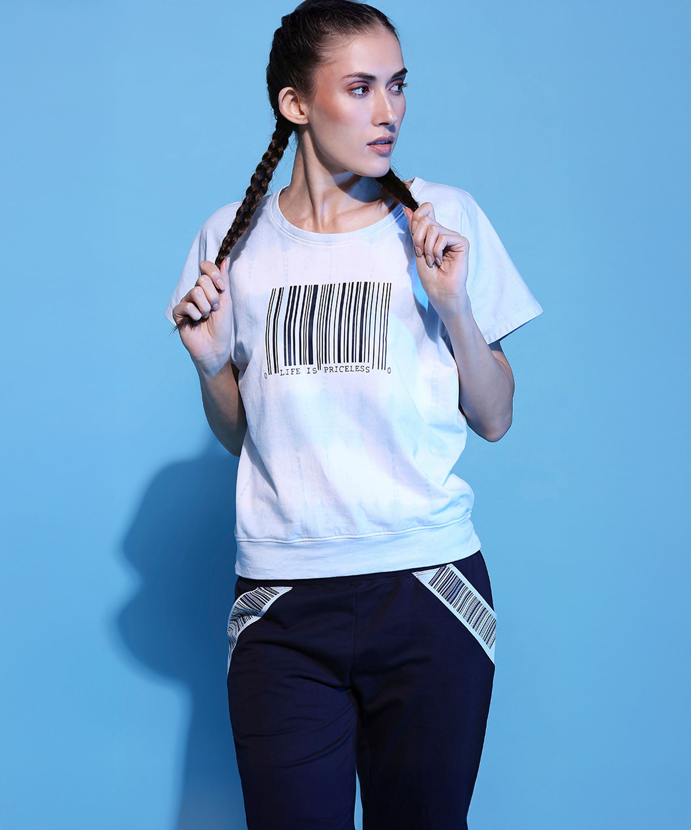 Woman with braided hair poses in the Barcode Printed Comfort Tie Dye Tee + Joggers - AW21 against a solid blue background.