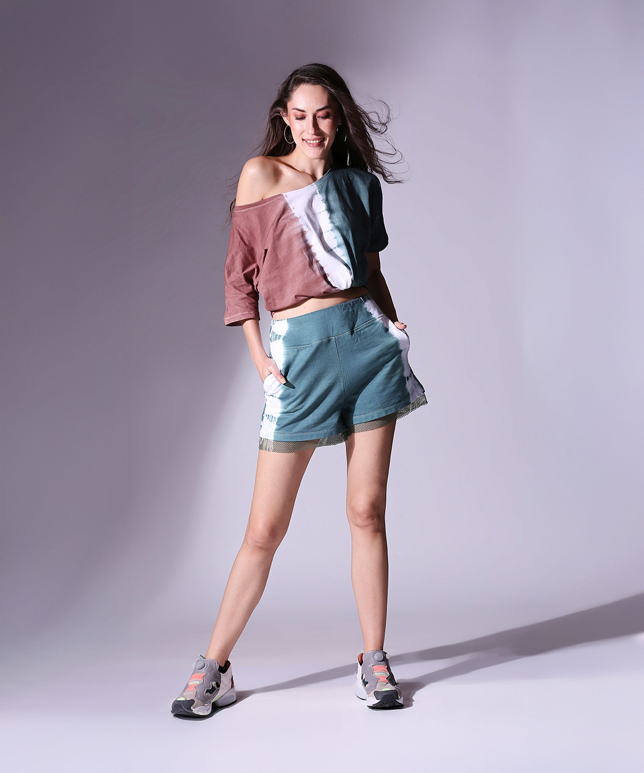Woman poses in the Oversized Comfort Tee + Shorts - AW21, smiling with hands in pockets, wearing this casual and stylish set.