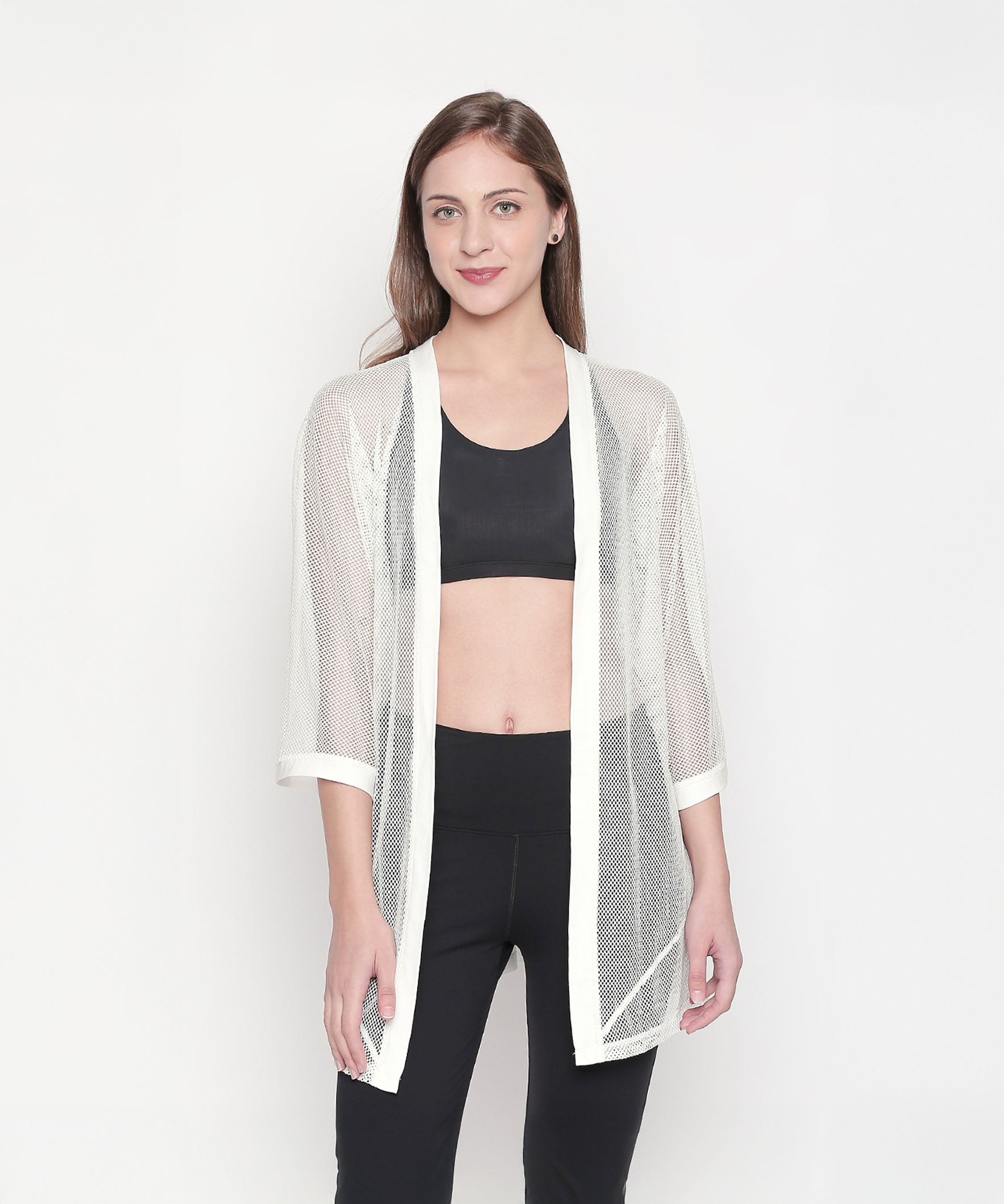 Model styling the Loose Fit 3/4th Sleeve White Shrug for Women over a black crop top and pants, set against a white background for an easy athleisure look.