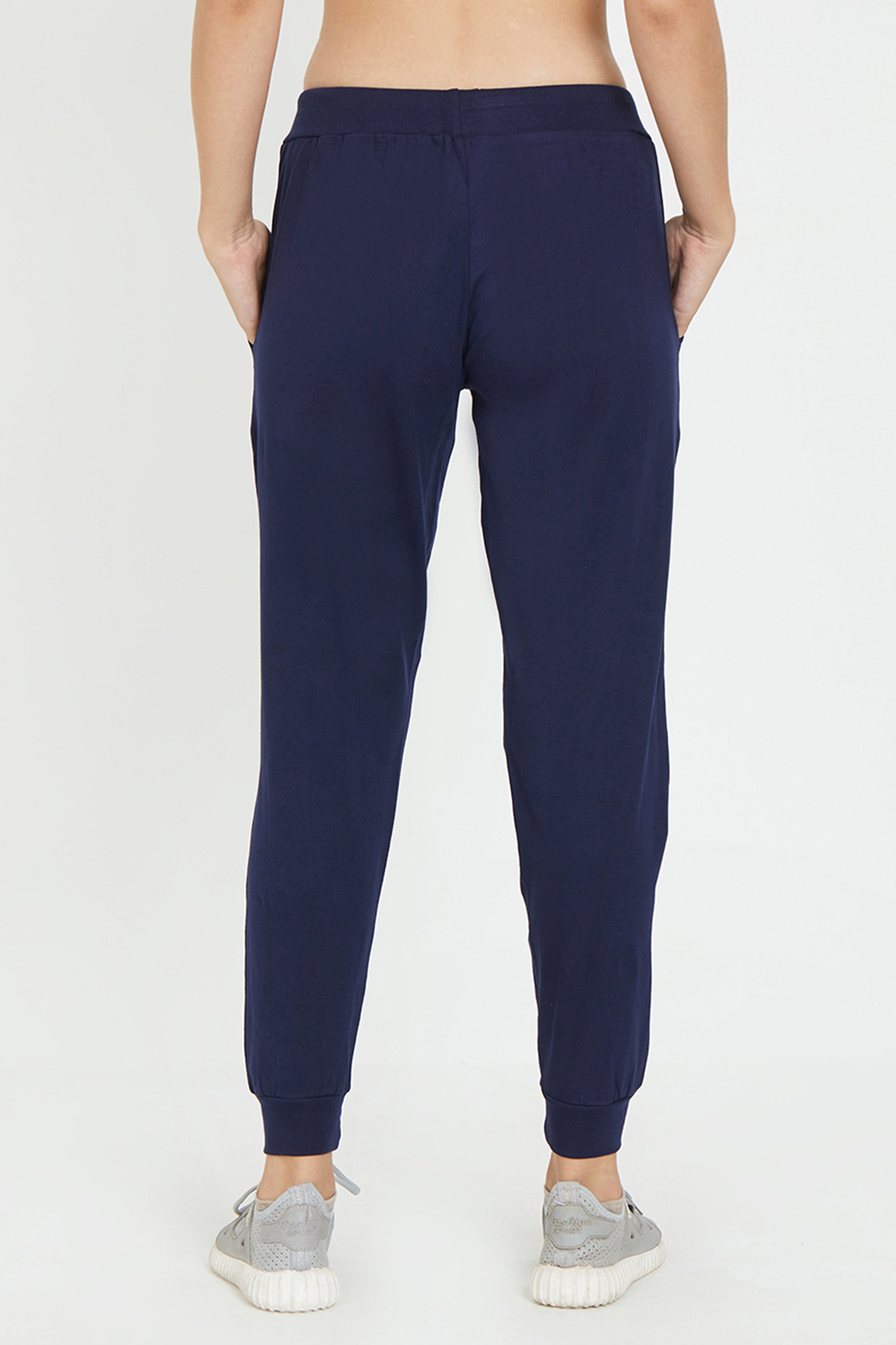 Person wearing Ashtanga Series Blue Joggers with gray sneakers, shown from the back against a plain white background.