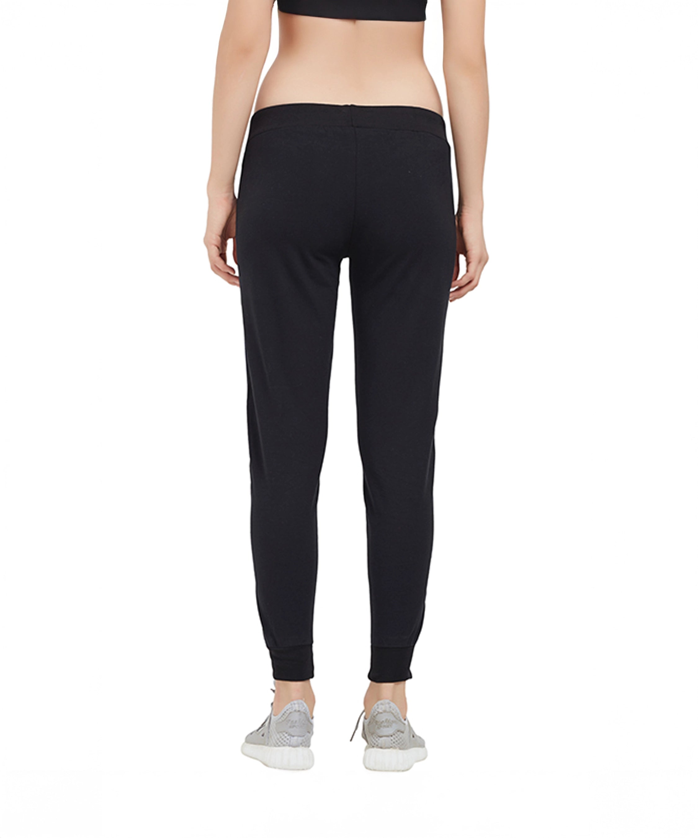 Person wearing black Classic Joggers TLC02SS with a tapered fit, paired with a black crop top and gray sneakers, shown from the back.