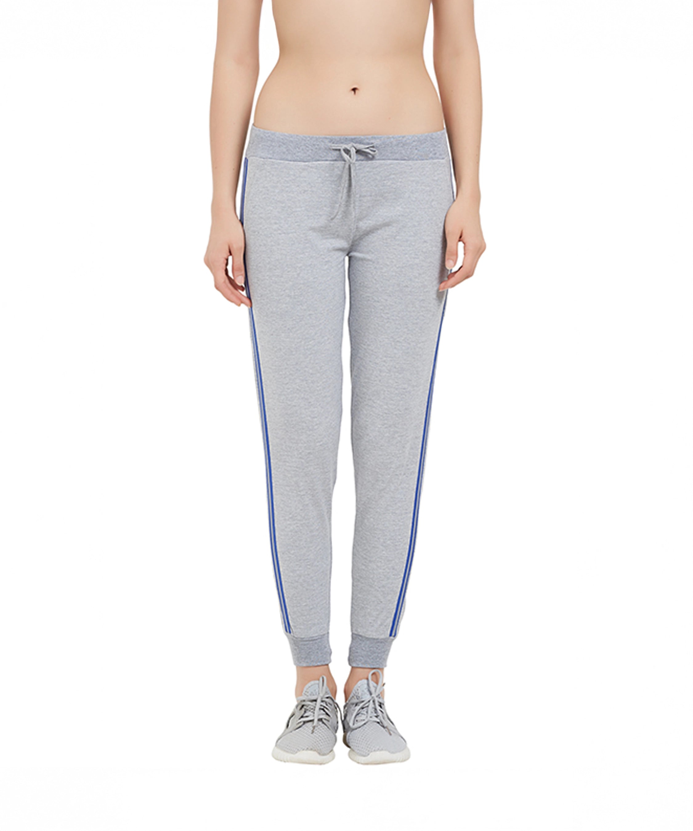 A woman wearing Side Stripe Joggers TLC03SS with blue side stripes and gray sneakers stands against a white background.