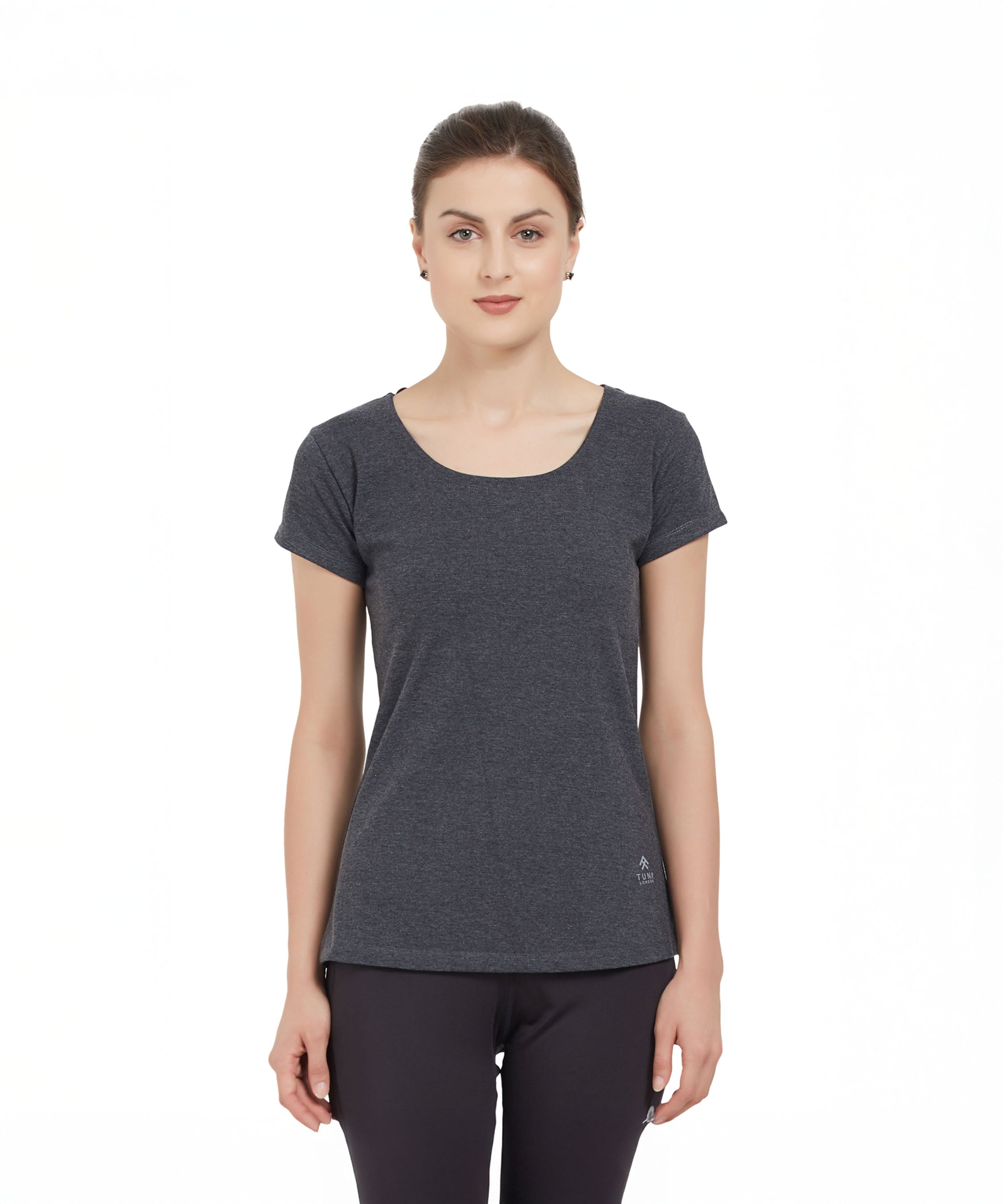 Woman wearing a TUNA LONDON Grey Round Neck Tee and black pants, standing against a white background.