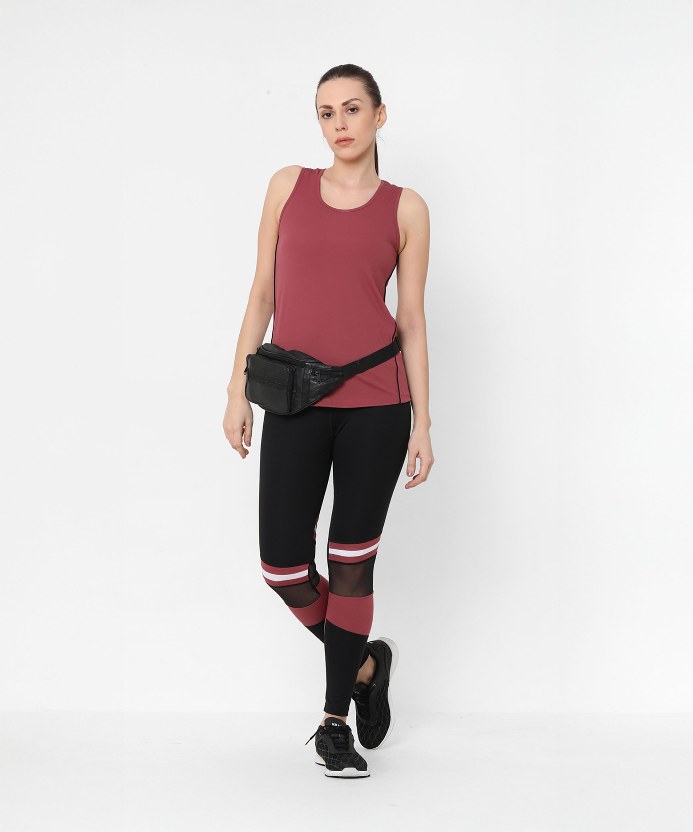 Woman in a maroon tank top, Sienna Black High Waisted Leggings with maroon stripes, black sneakers, and a black waist bag.