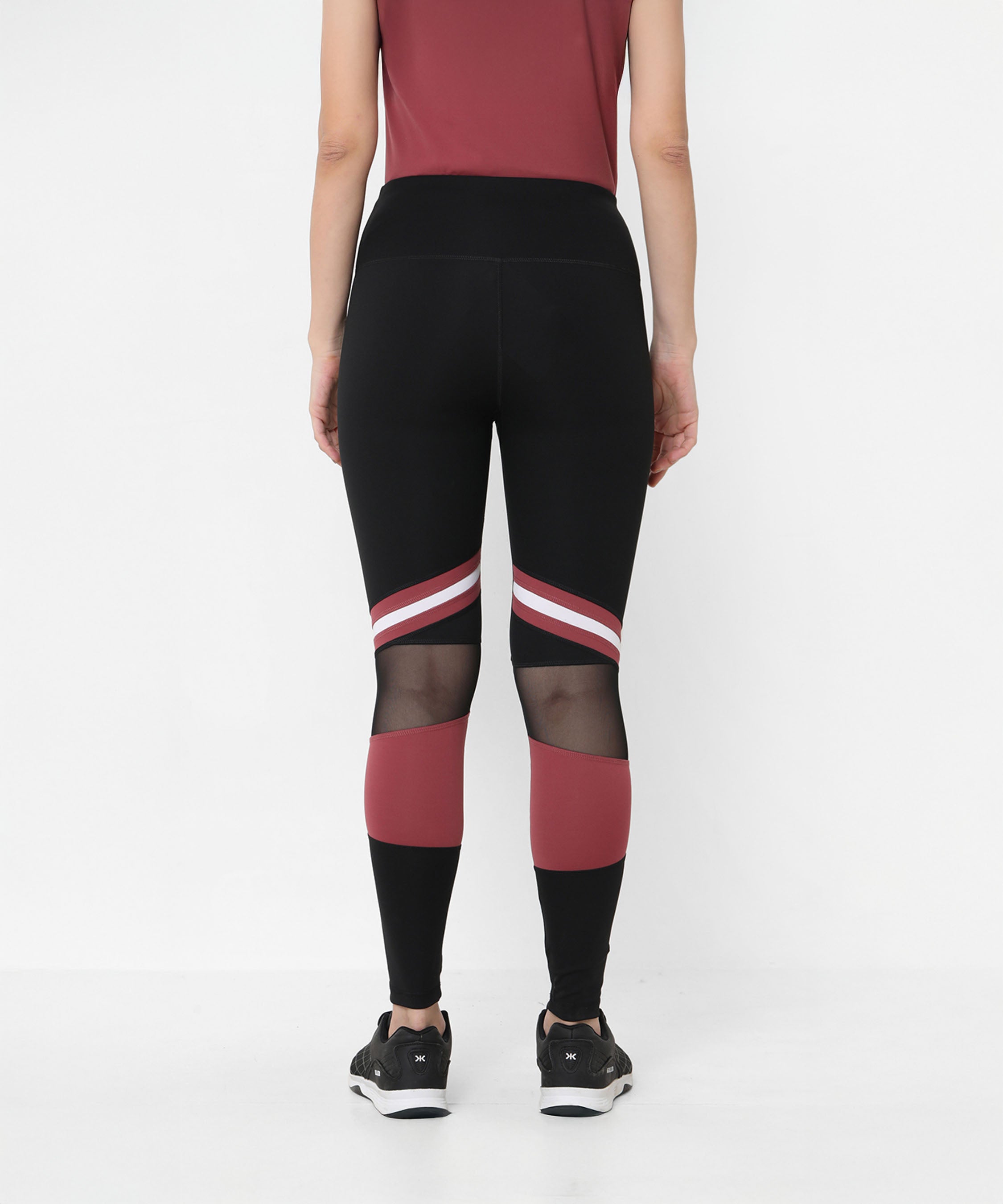 Model wearing Sienna Black High Waisted Leggings with red and white stripes, mesh panels, and four-way stretch, standing with back to camera.