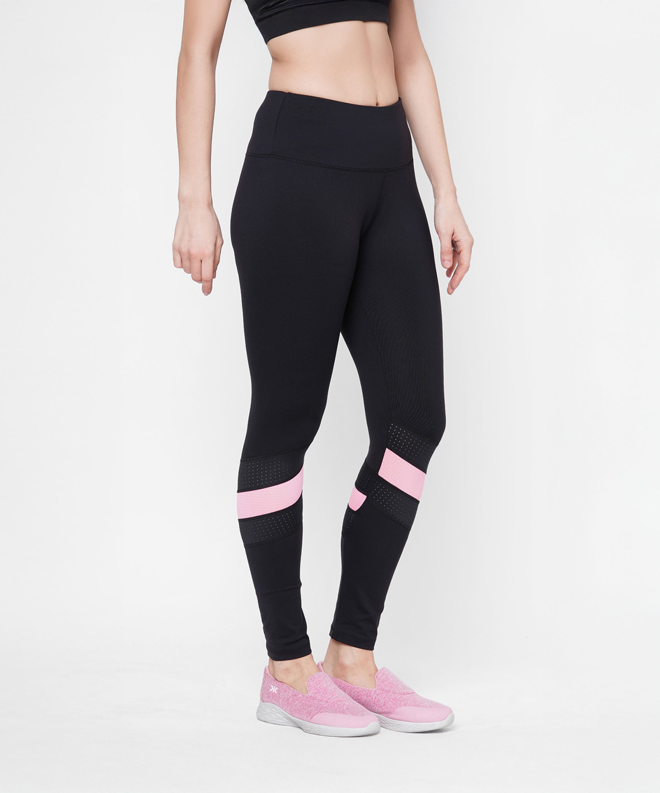 A woman models the Black High Waisted Compression Legging With a Neon Pink Patch and matching pink shoes, standing against a white background. Four-way stretch compression fabric provides a flattering, comfortable fit.