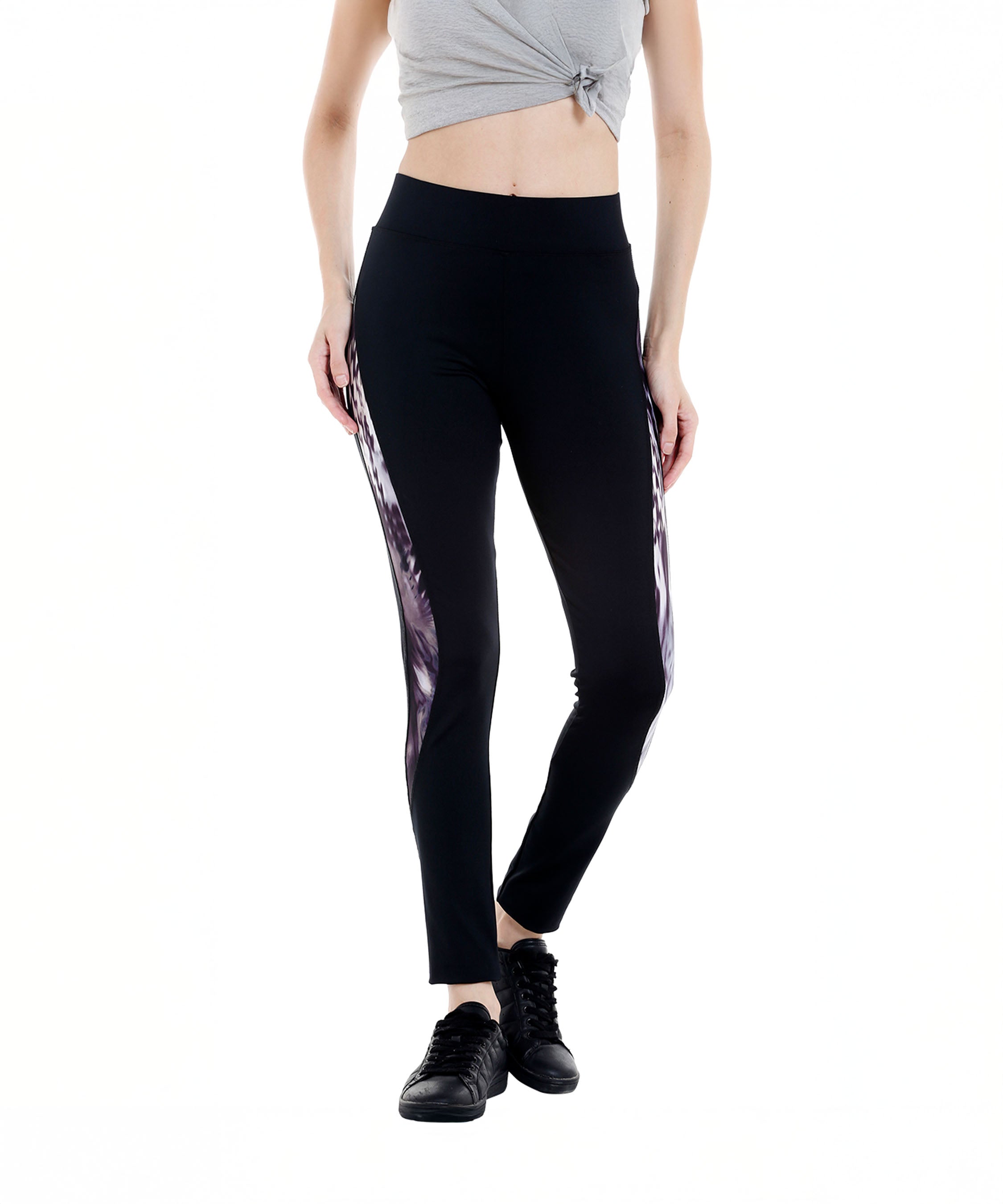 Woman in a gray crop top and Black Sports Leggings G2 featuring an elasticated waistband and side patterns, paired with black sneakers, standing against a white background.