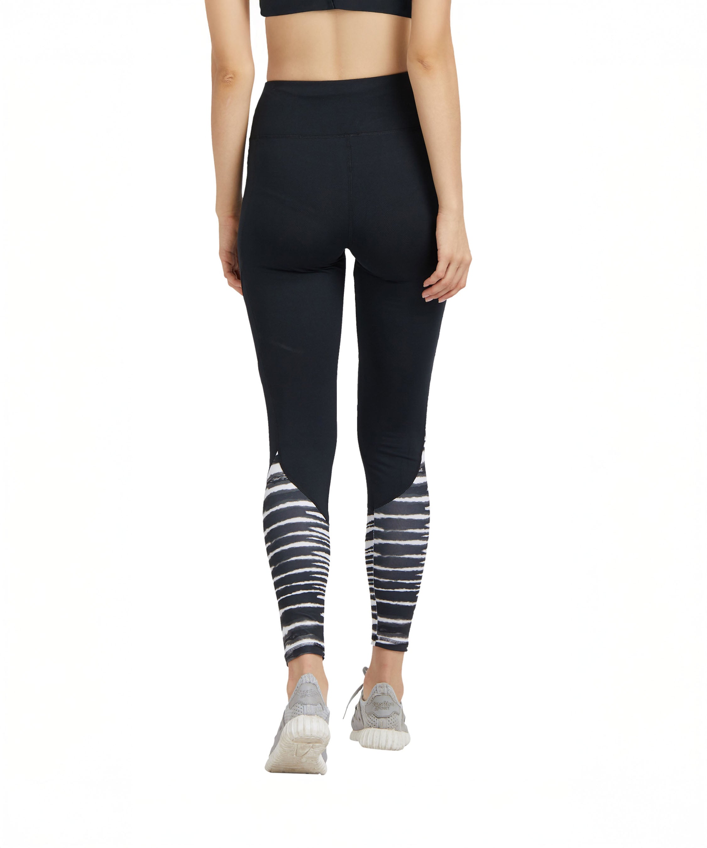 Woman seen from the back wearing Black High Waisted Compression Sports Leggings with zebra print and sneakers.