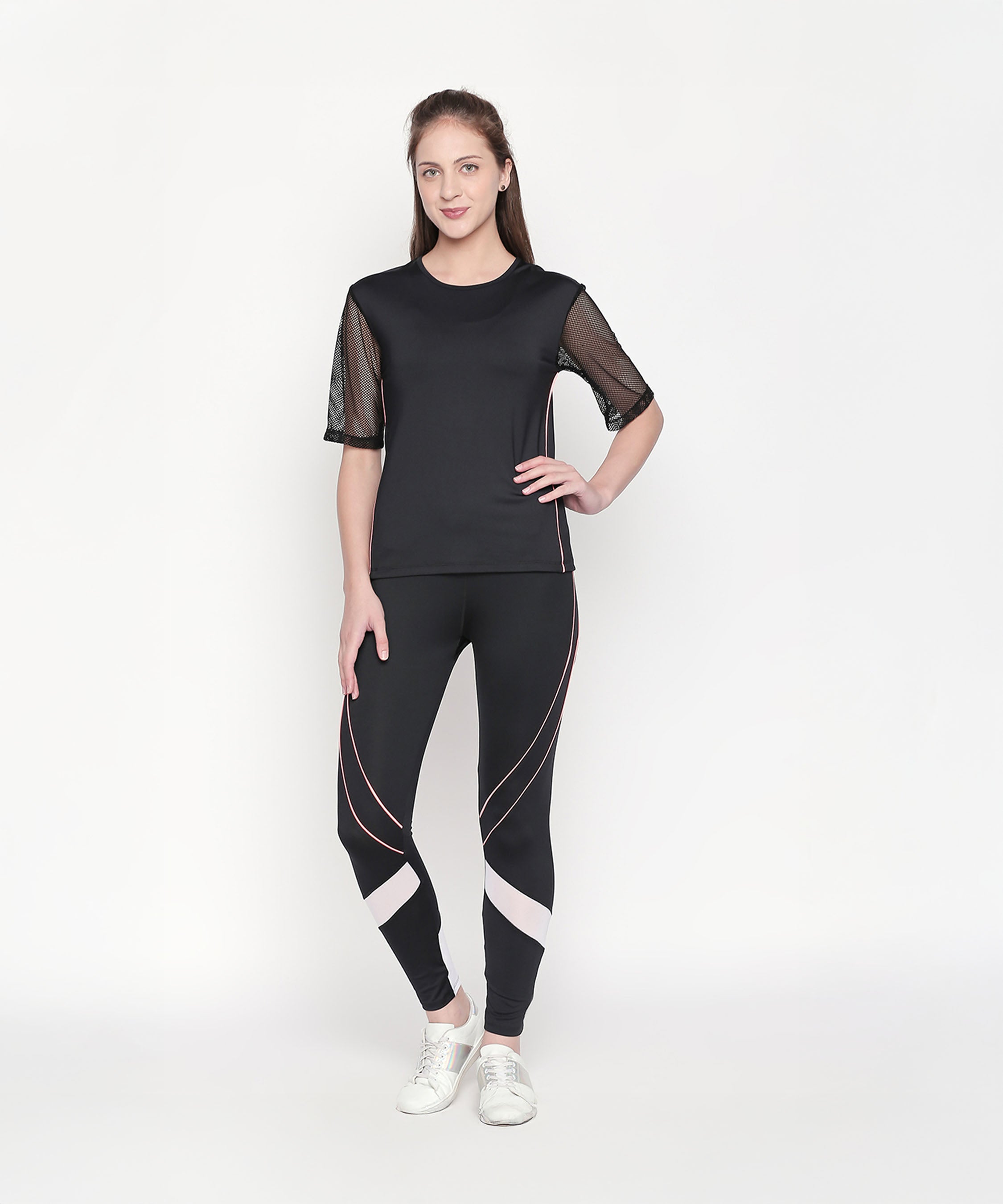 A woman wears the Black Loose Fit Round Neck Net Half Sleeve Top, paired with white sneakers, standing against a plain white background.